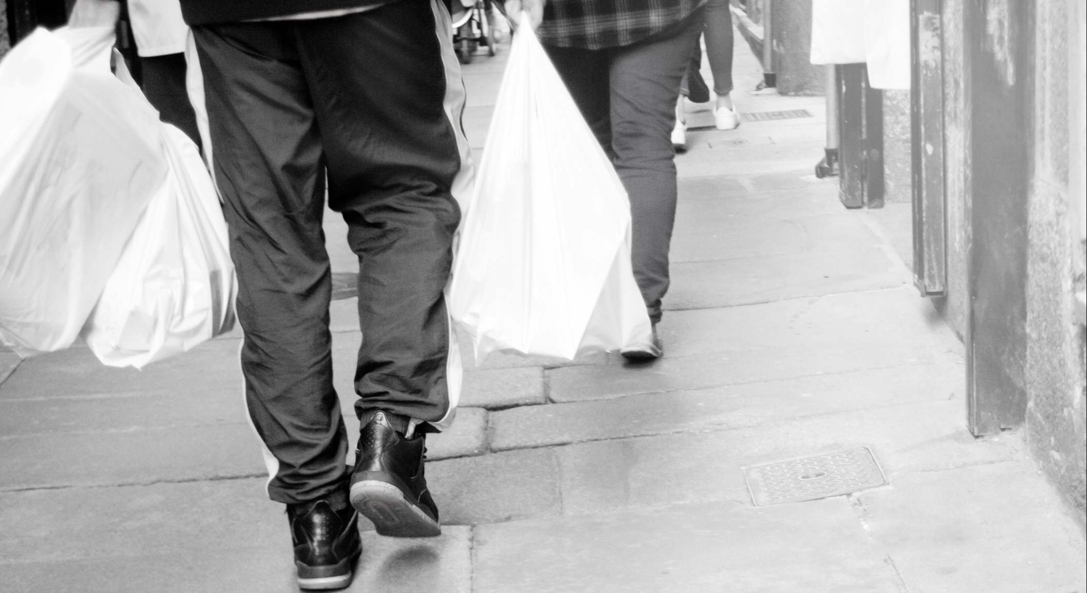 Gente cargando bolsas por la calle en una imagen en blanco y negro de iStock