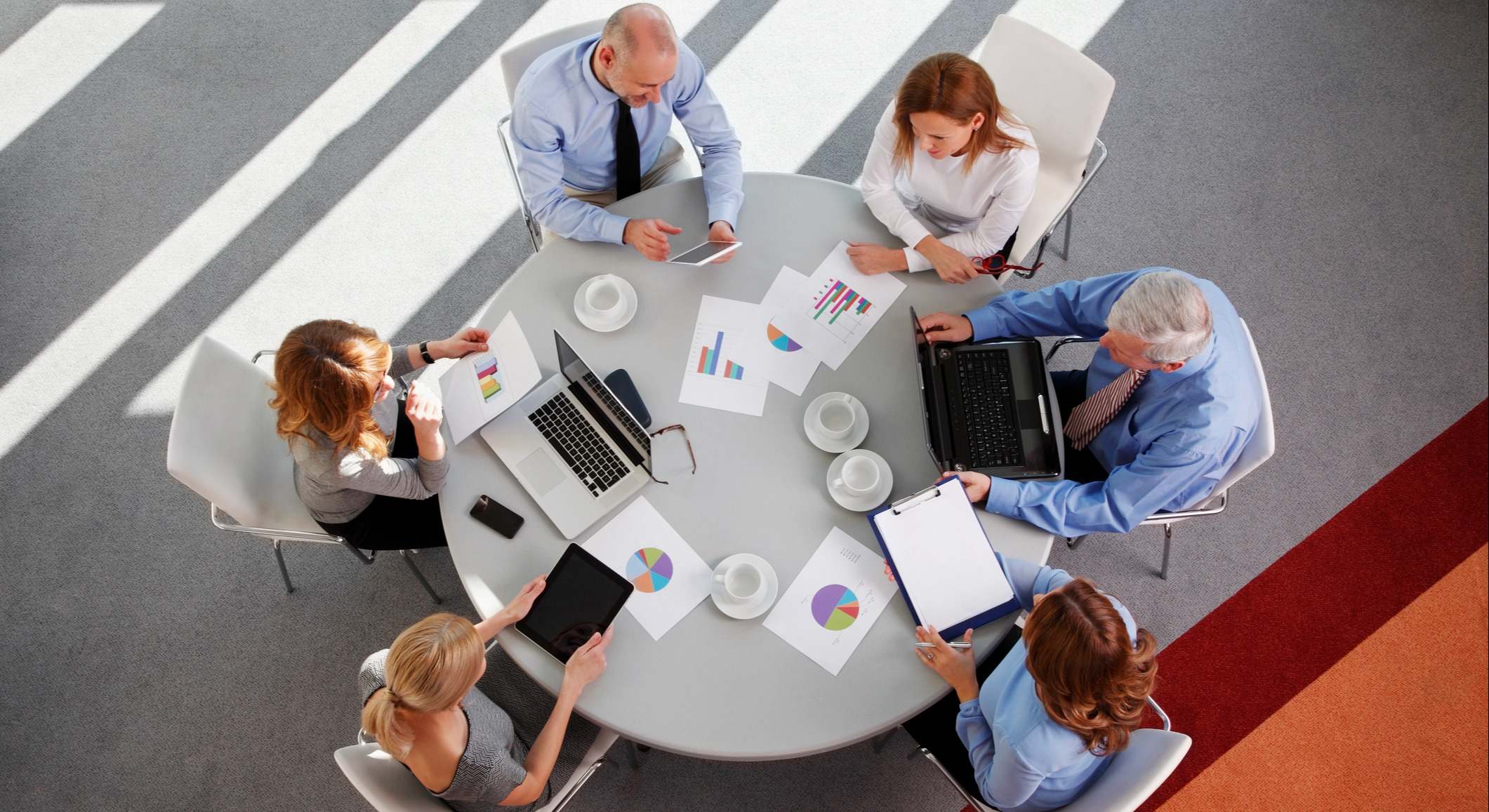 Equipo de ventas trabajando en una mesa redonda con gráficos