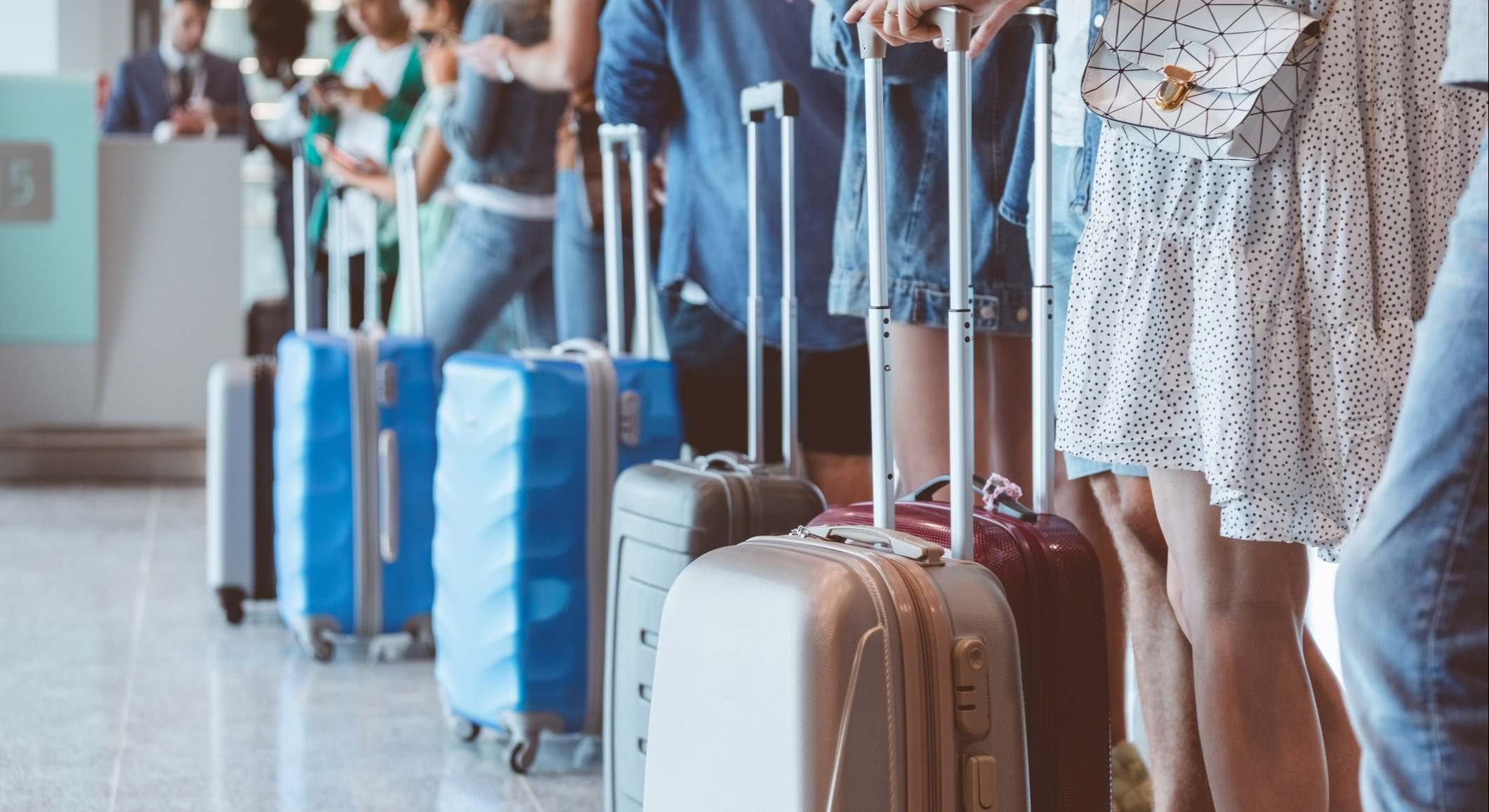 Pasajeros con equipaje esperando en la fila del aeropuerto