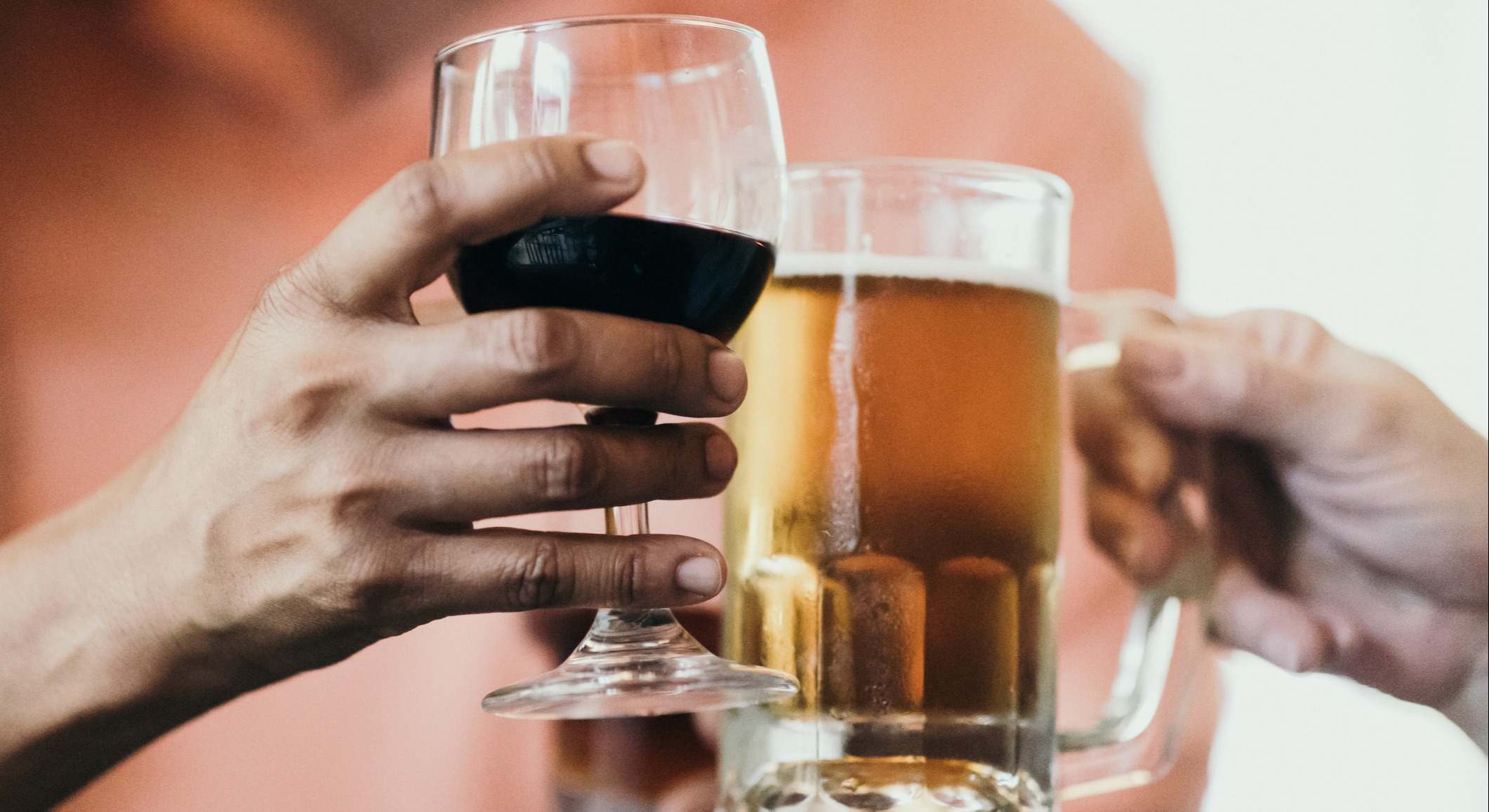 Personas brindando una copa de vino y una jarra de cerveza
