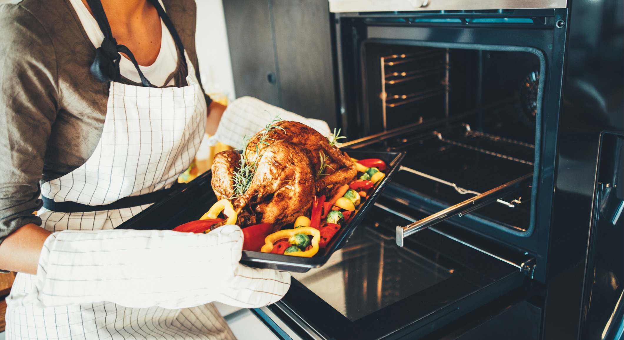 Mujer metiendo el pollo en el horno