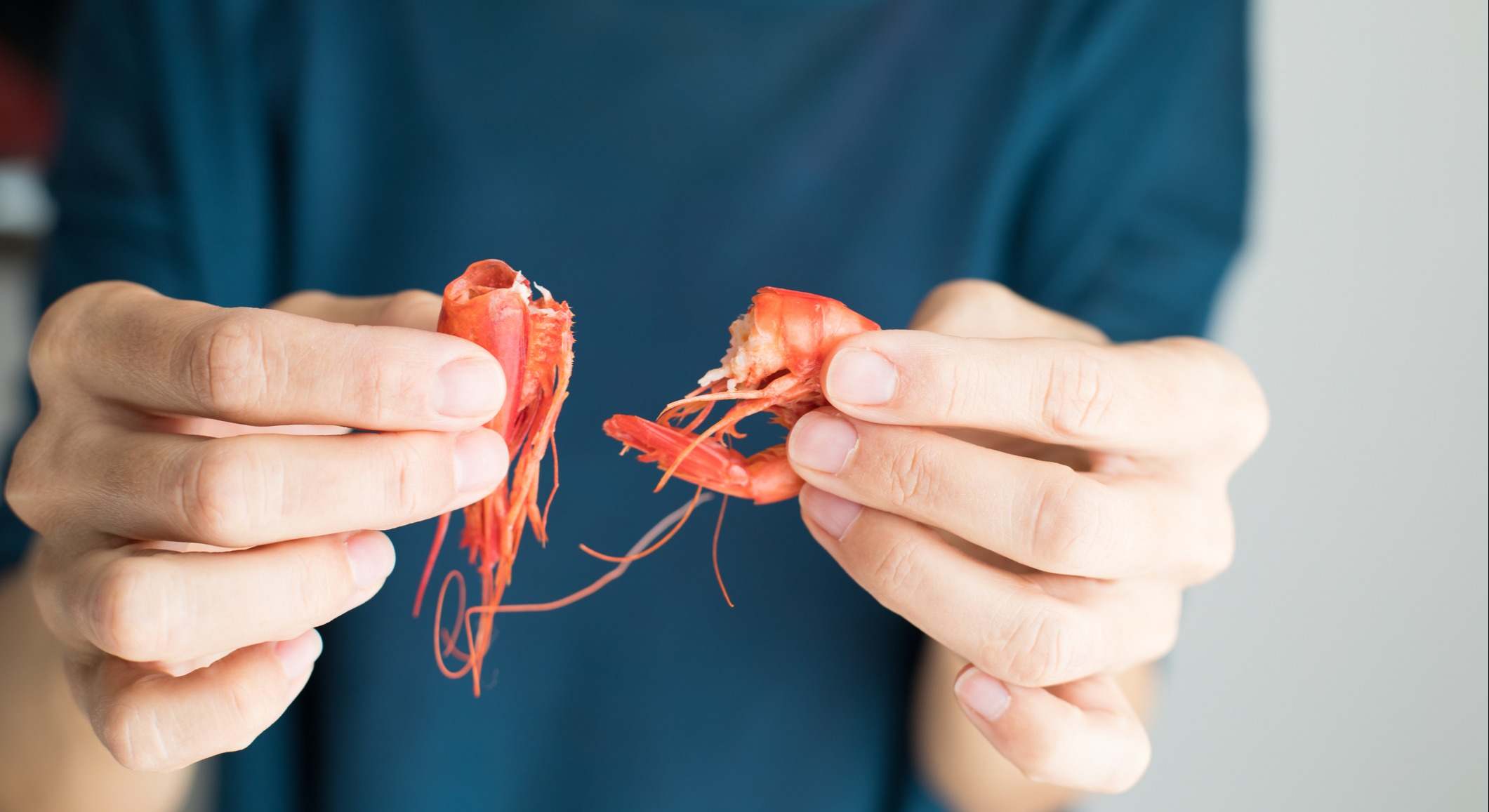 Manos de mujer pelando una gamba roja