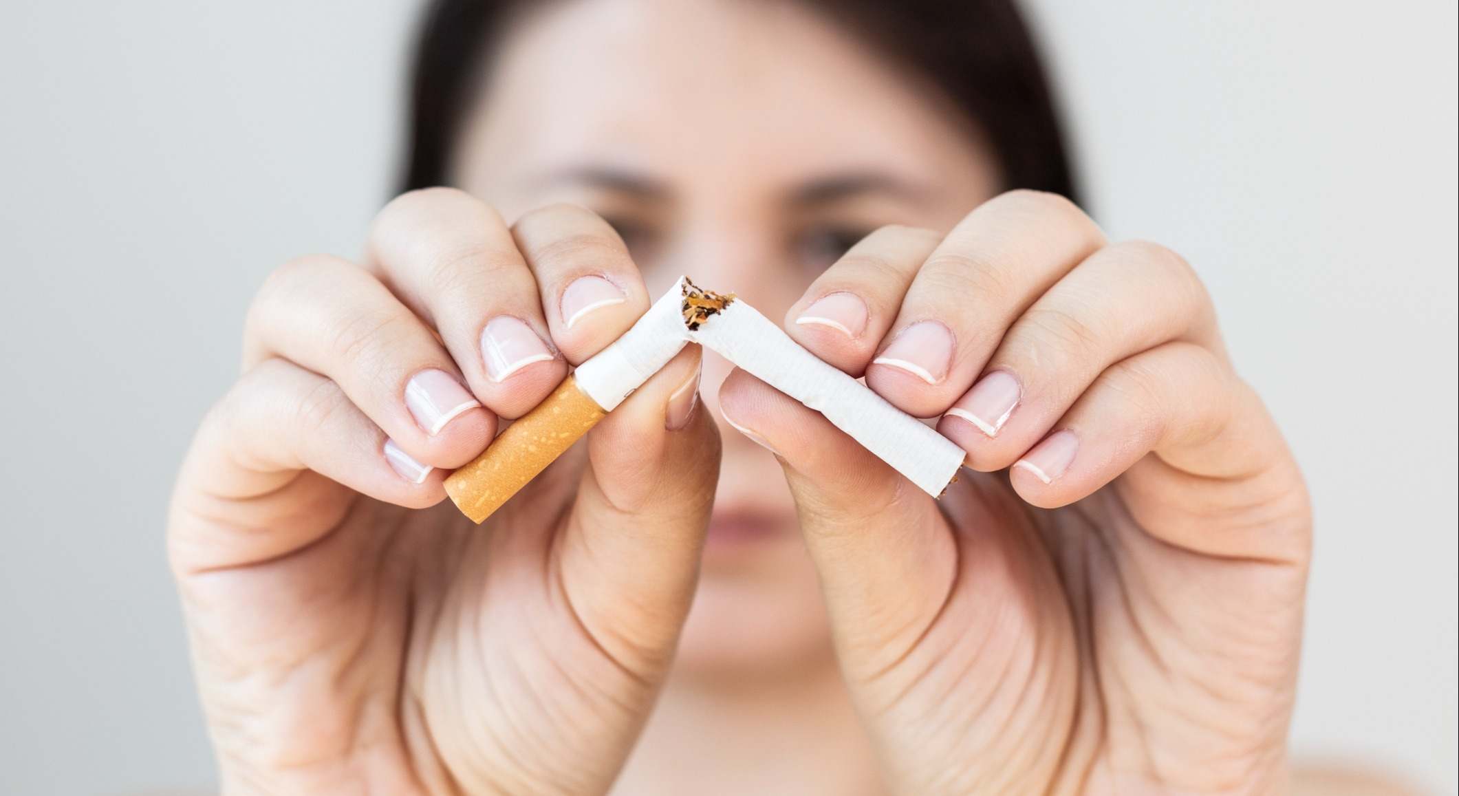 Mujer rompiendo un cigarrillo con sus manos a la mitad
