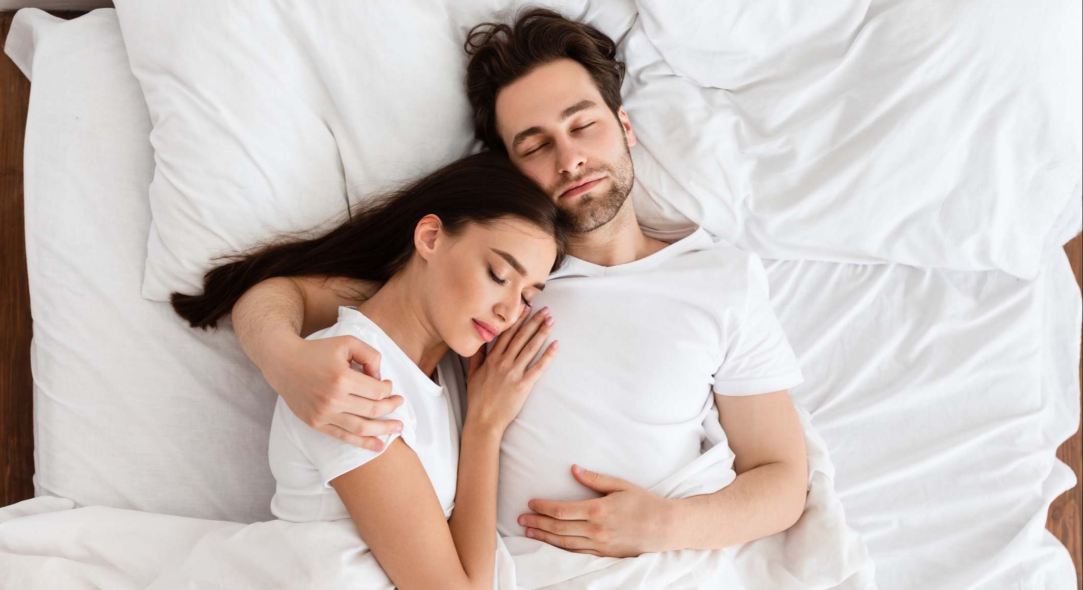 Pareja durmiendo abrazada en la cama