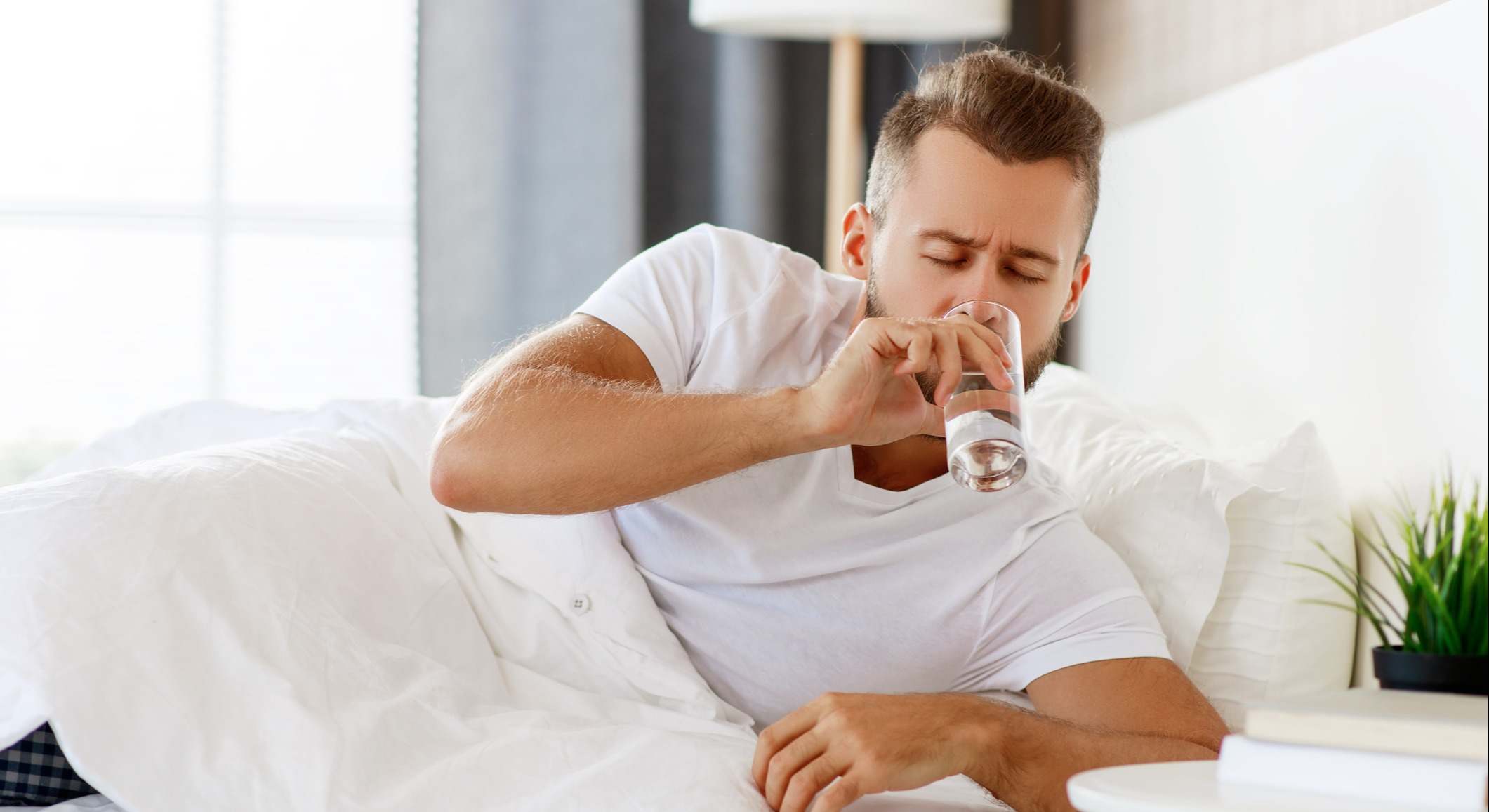 Hombre bebe agua en la cama al levantarse