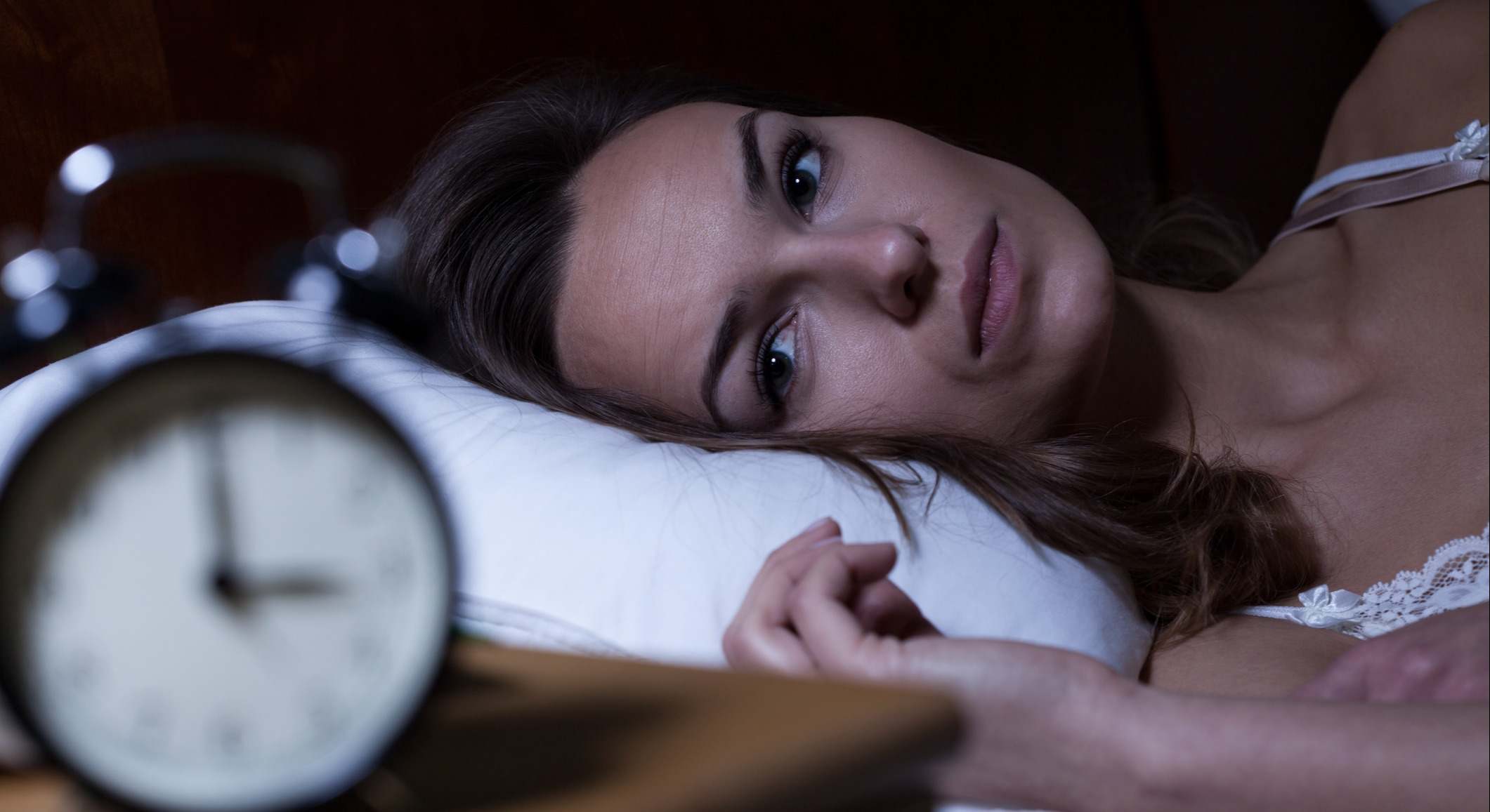 Mujer tumbada en la cama mirando el reloj