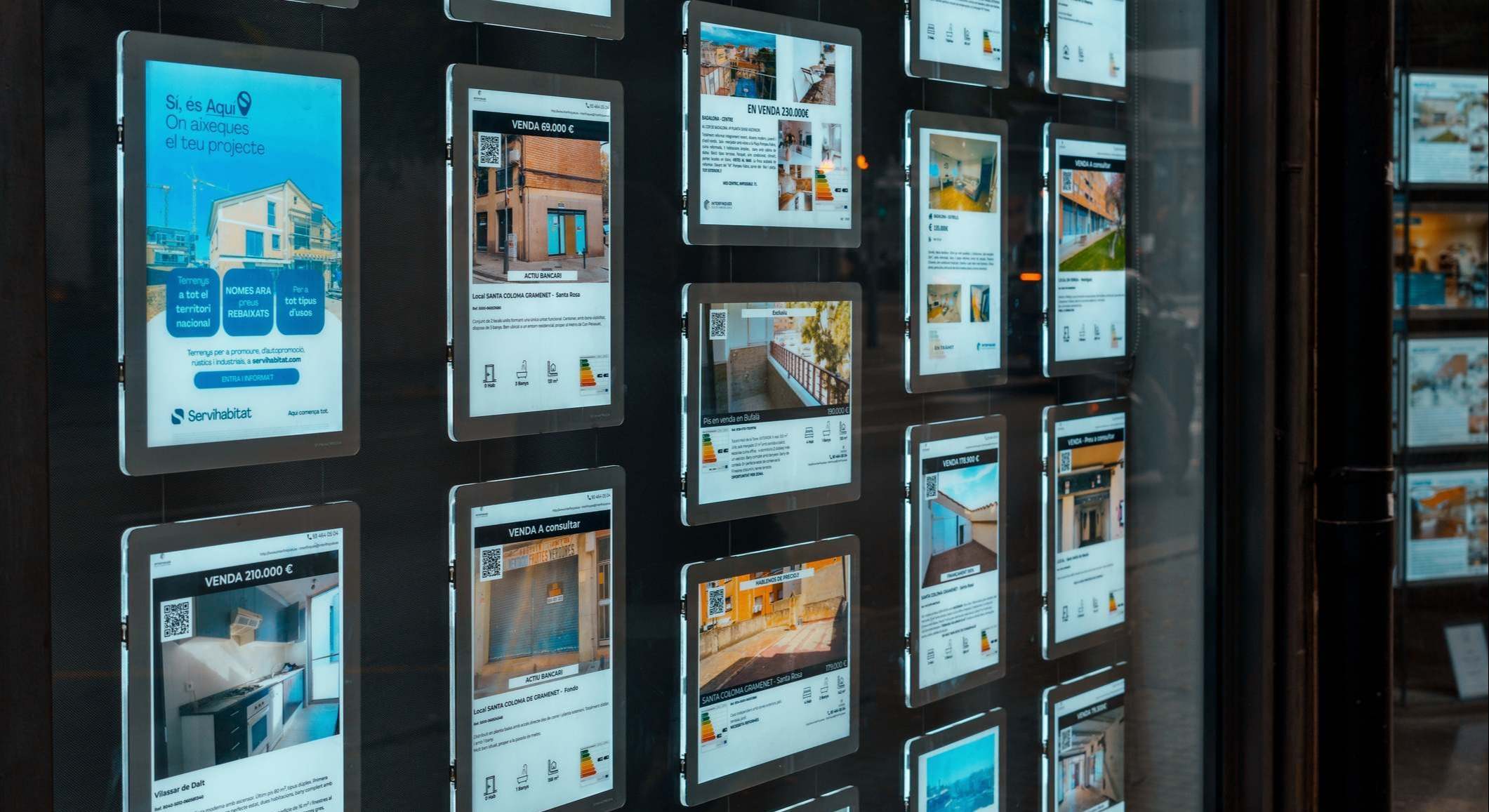 Escaparate de una agencia inmobiliaria con anuncios de pisos en venta o alquiler.