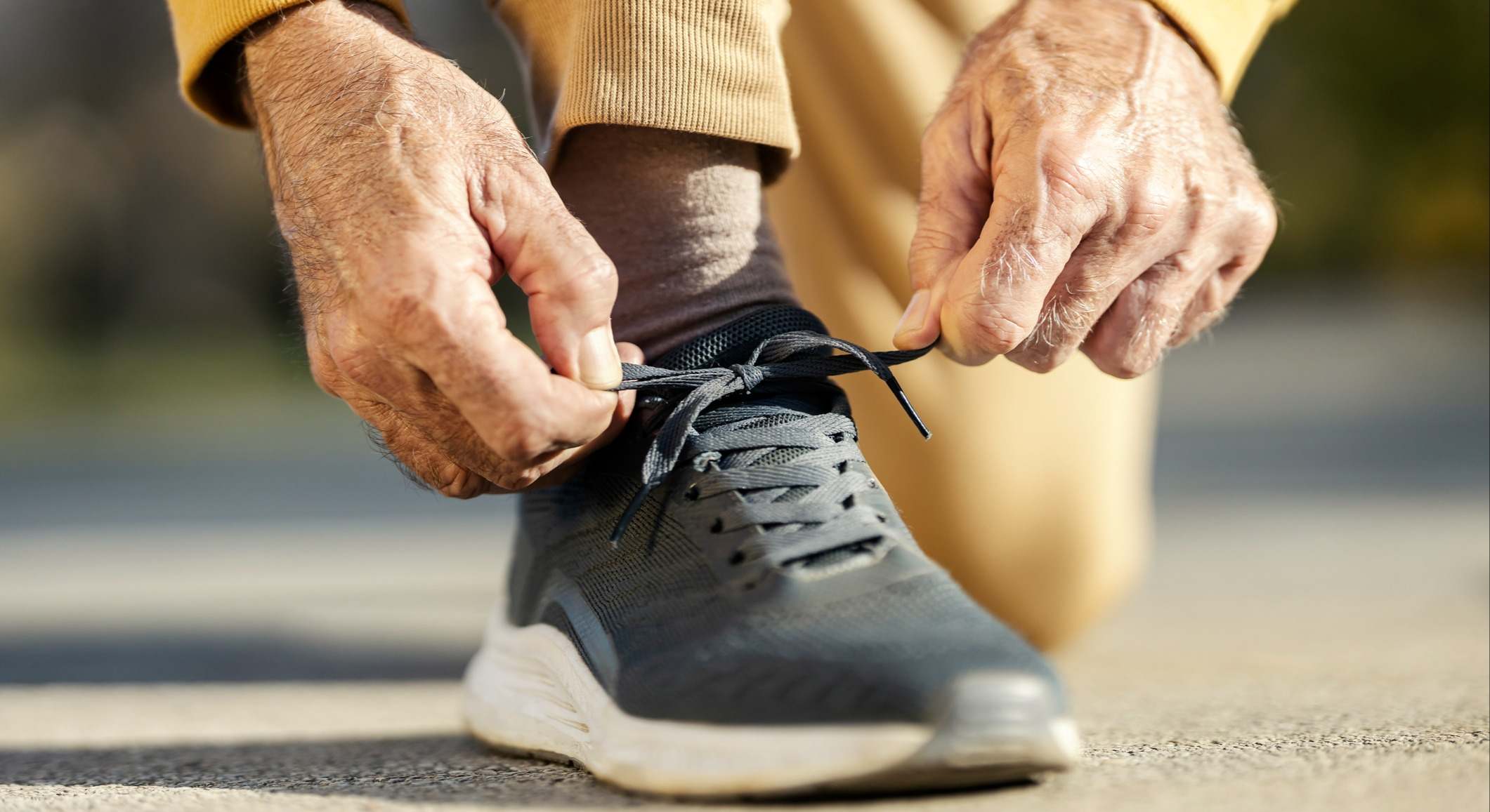 Manos de un anciano atándose los zapatos