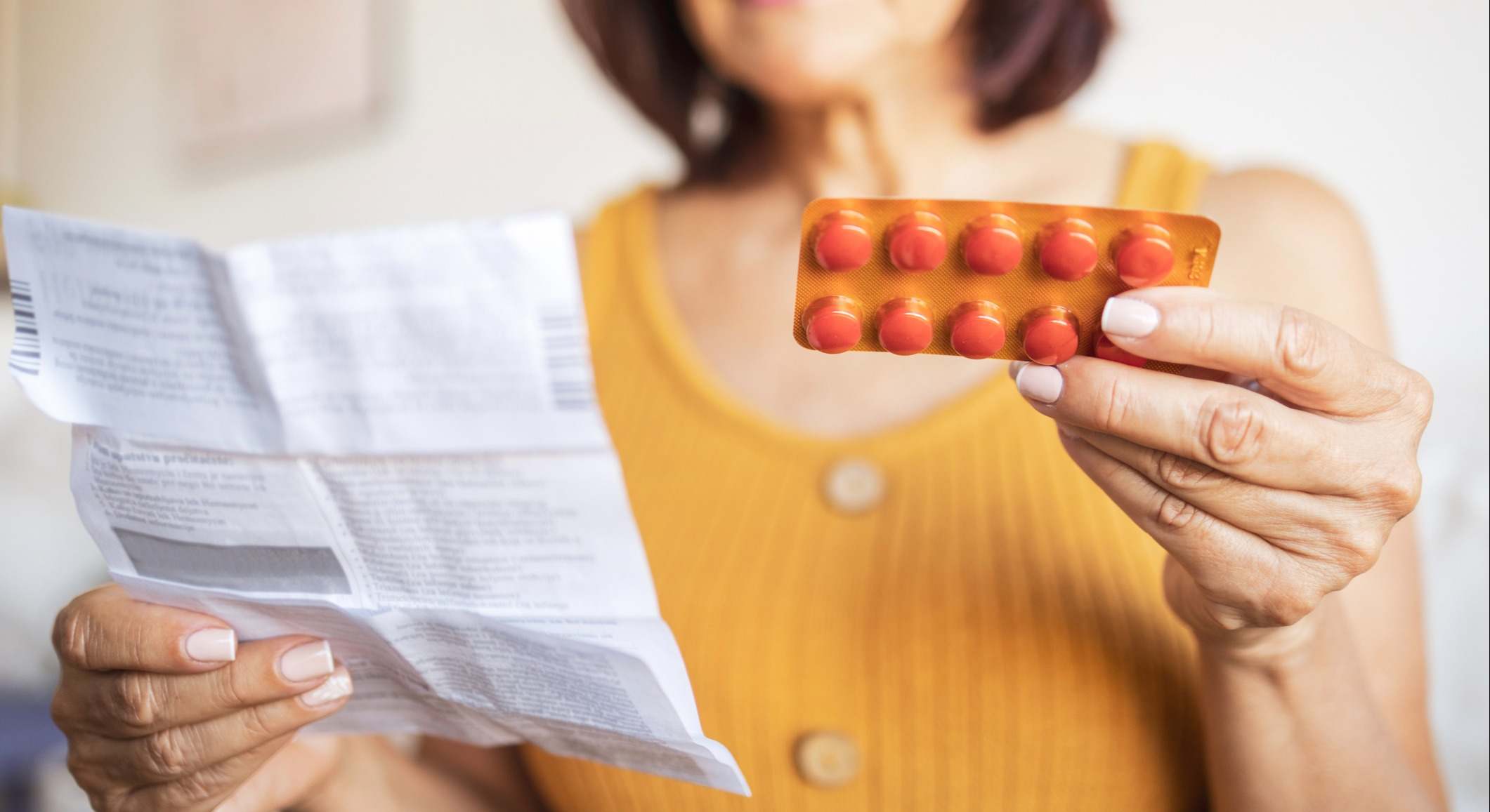 Primer plano de una mujer revisando el prospecto de información para el paciente para su medicamento.