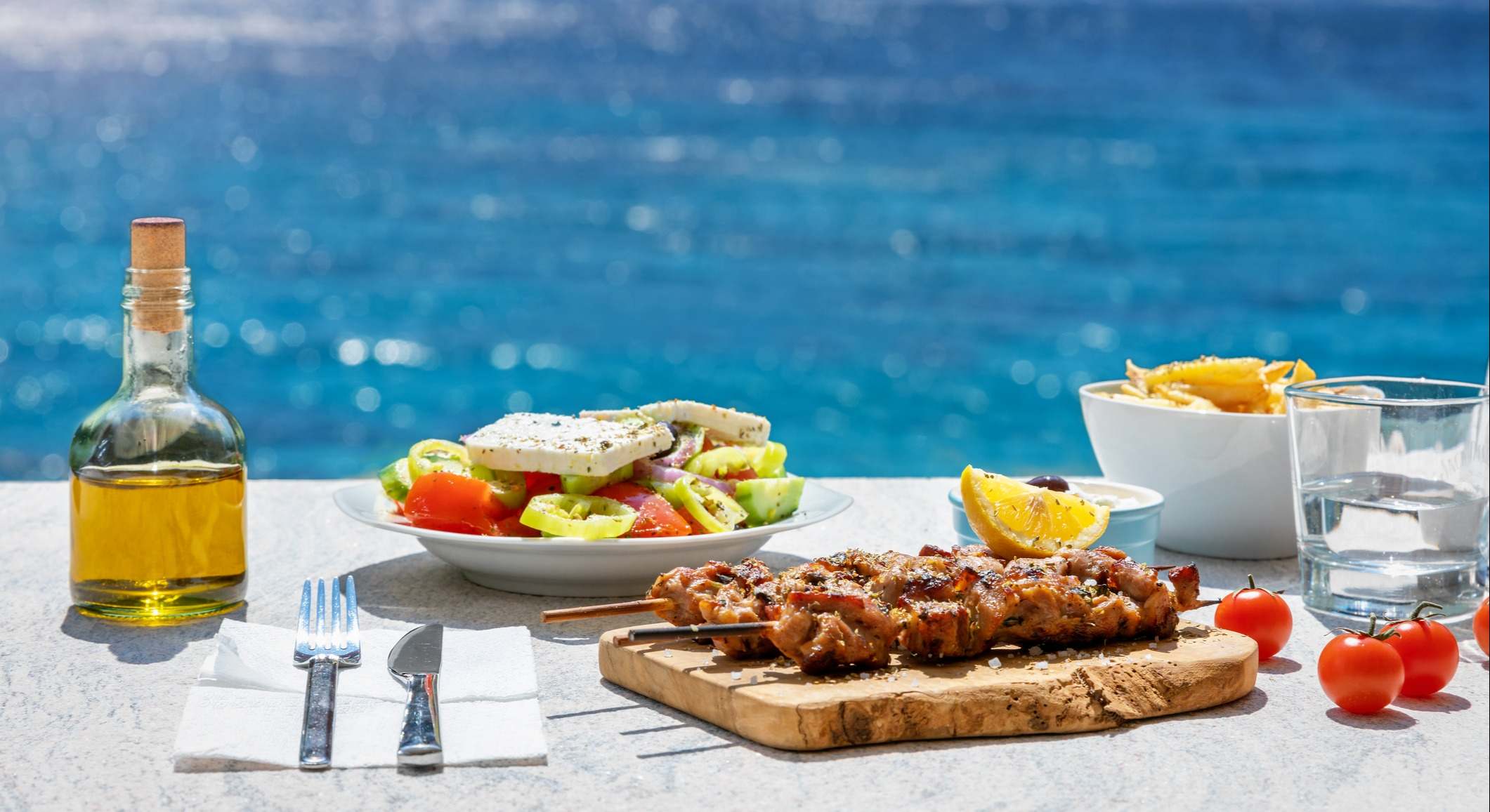 Comida griega sobre la mesa con el mar de fondo