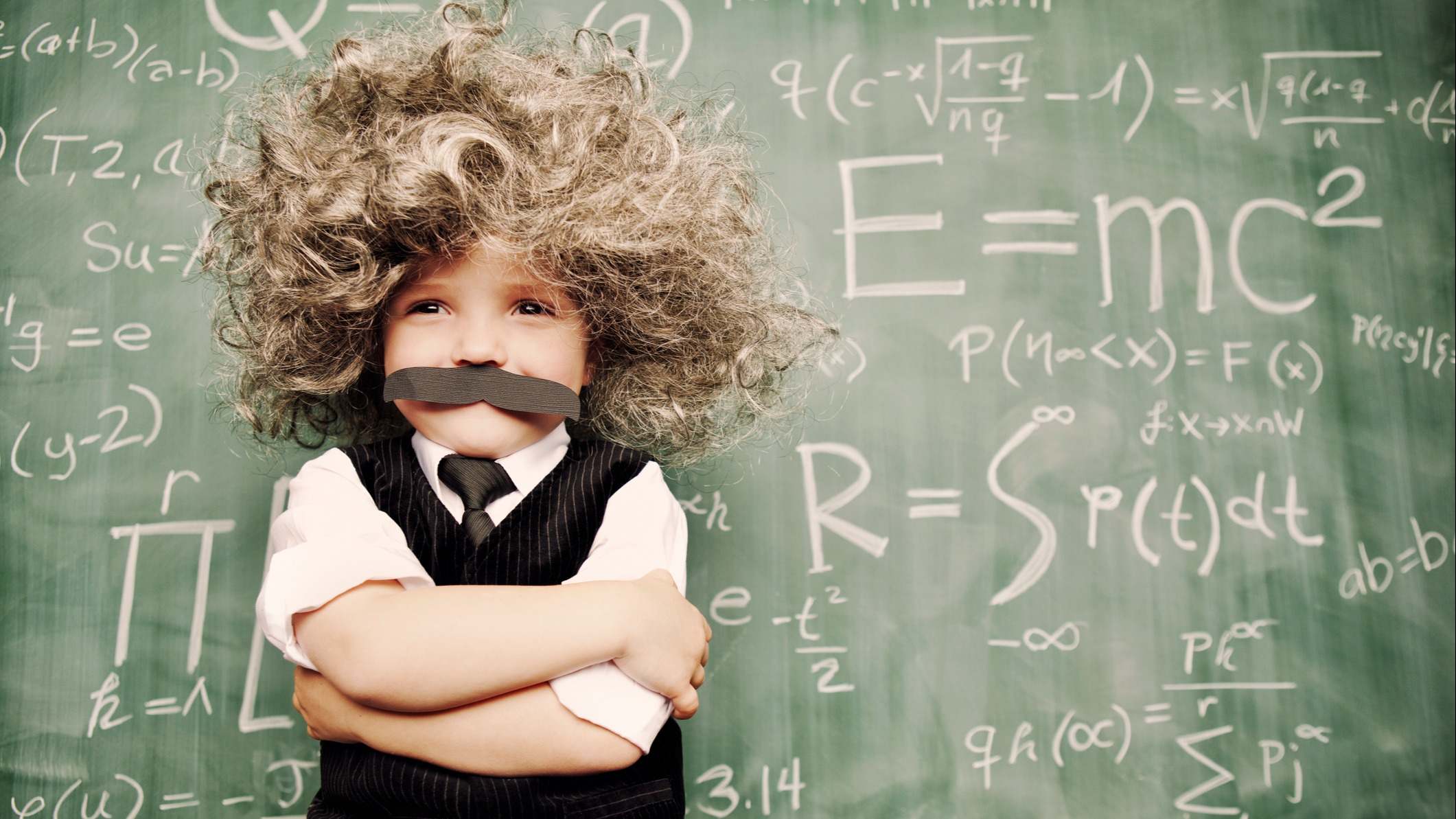 Niño disfrazado con de Albert Einstein con una pizarra detrás