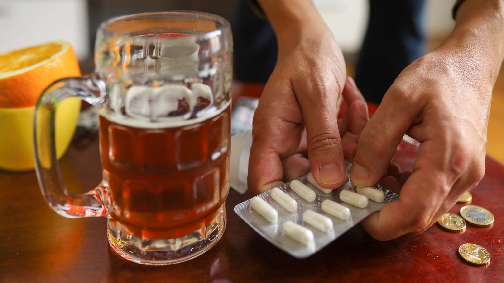 Medicamentos y una jarra de cerveza sobre una mesa de madera