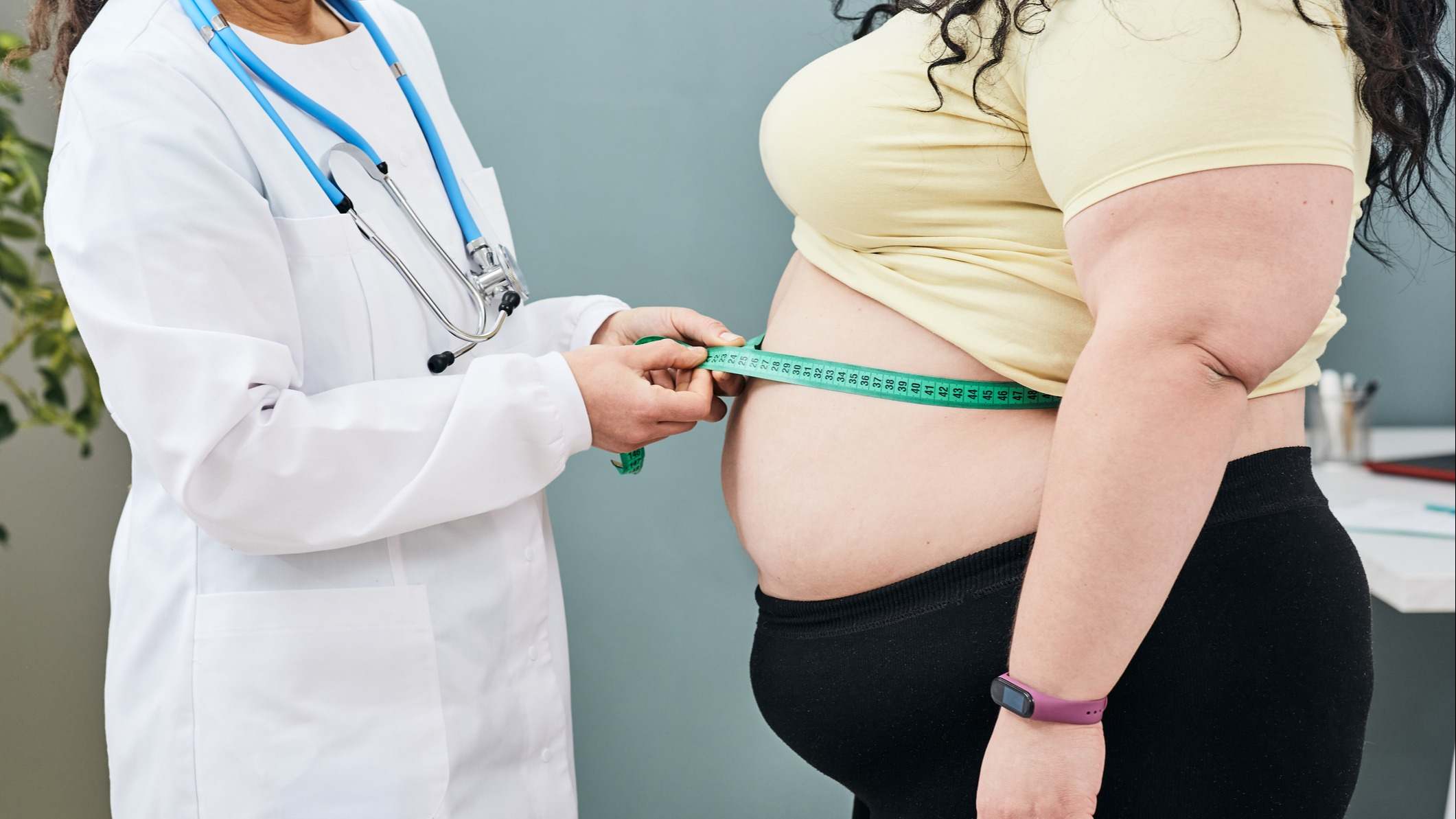 Médico midiendo la cintura a una paciente con obesidad.