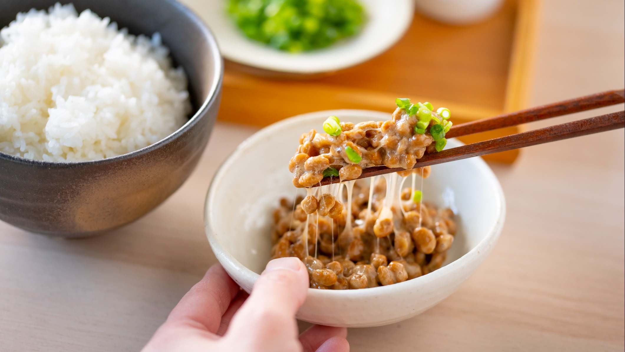 Persona comiendo natto con palillos de un cuenco