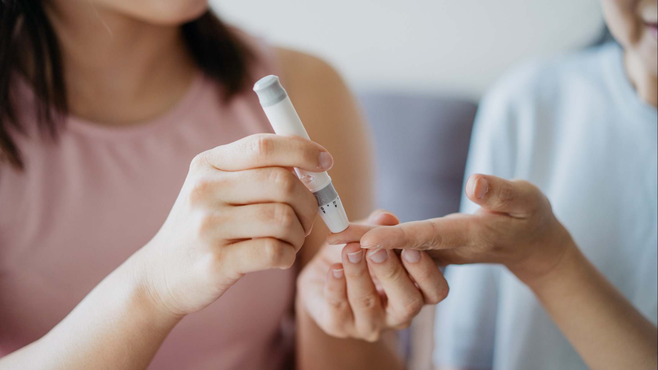 Mujer ayuda a otra a controlar el nivel de azúcar en la sangre usando un medidor de glucosa en sangre