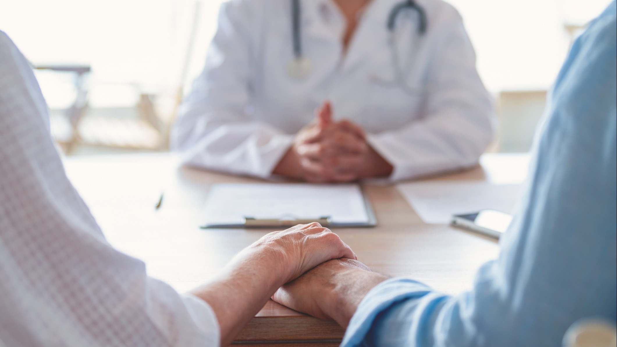 Pareja de mediana edad tomada de la mano en una consulta de un médico