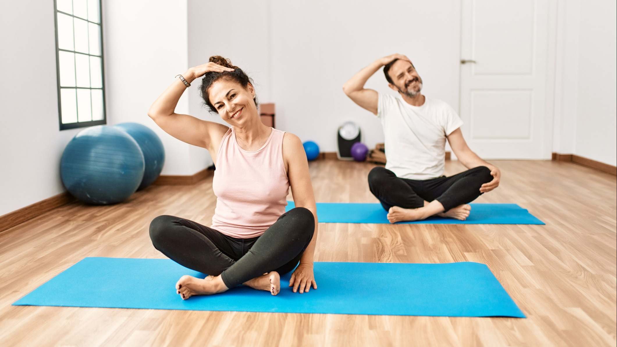 Pareja haciendo deporte sobre una esterilla en el interior de su casa