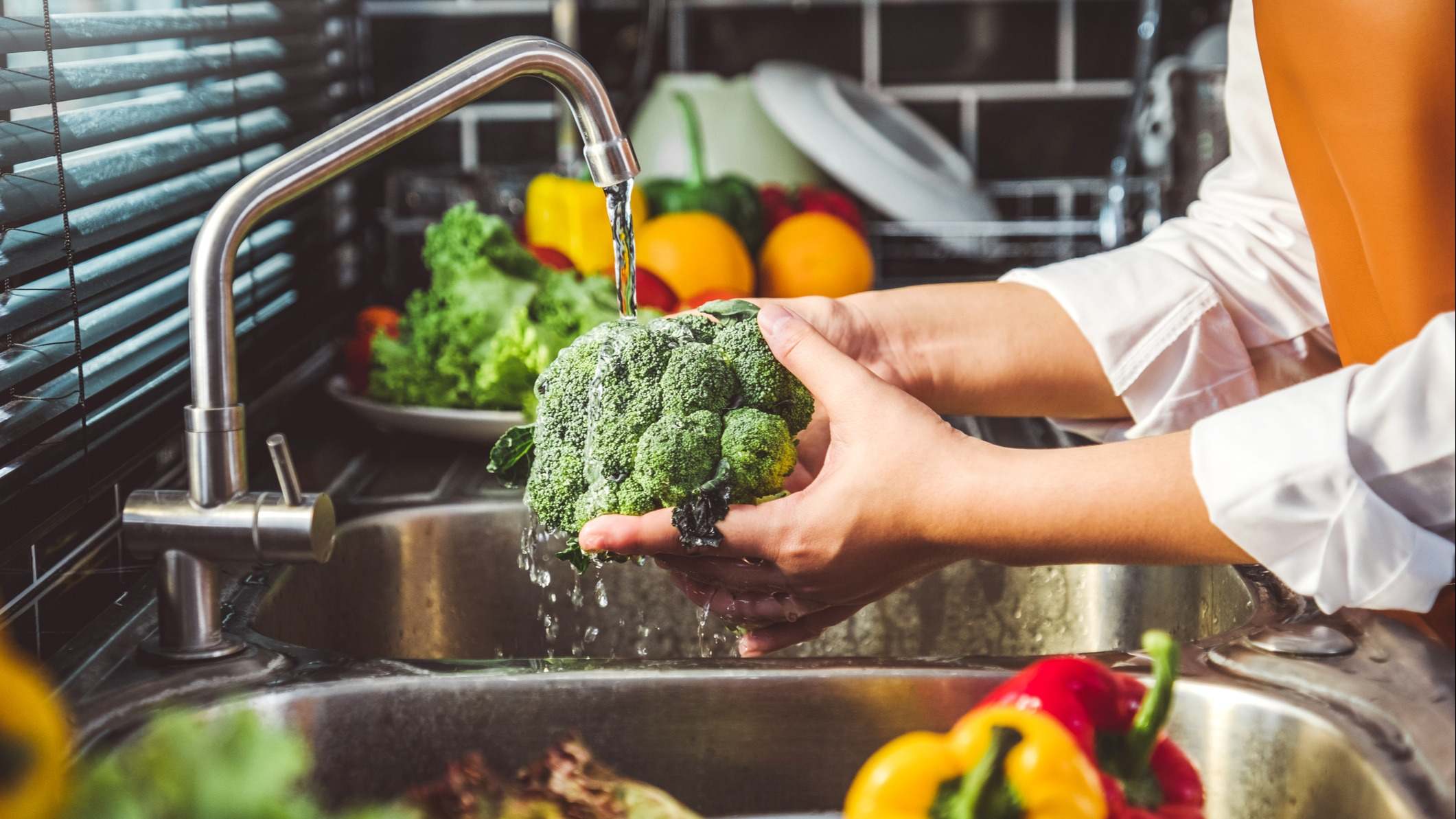 Mano lavando un brócoli en el fregadero de la cocina