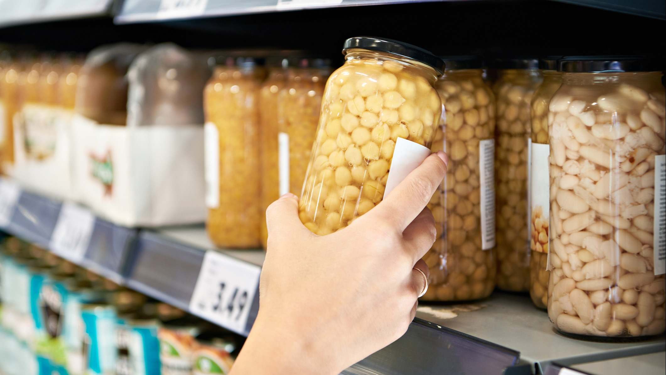 Persona cogiendo un bote de garbanzos en un supermercado