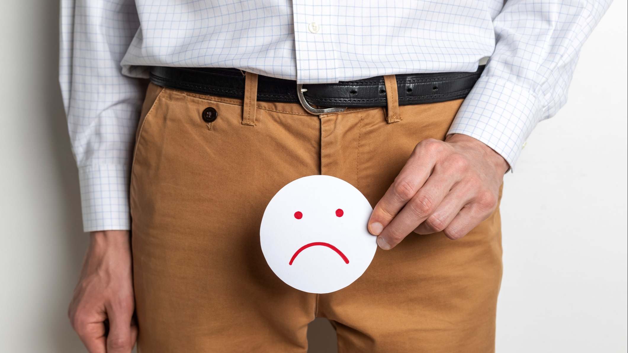 Hombre sosteniendo una cara triste encima delante de su pantalón