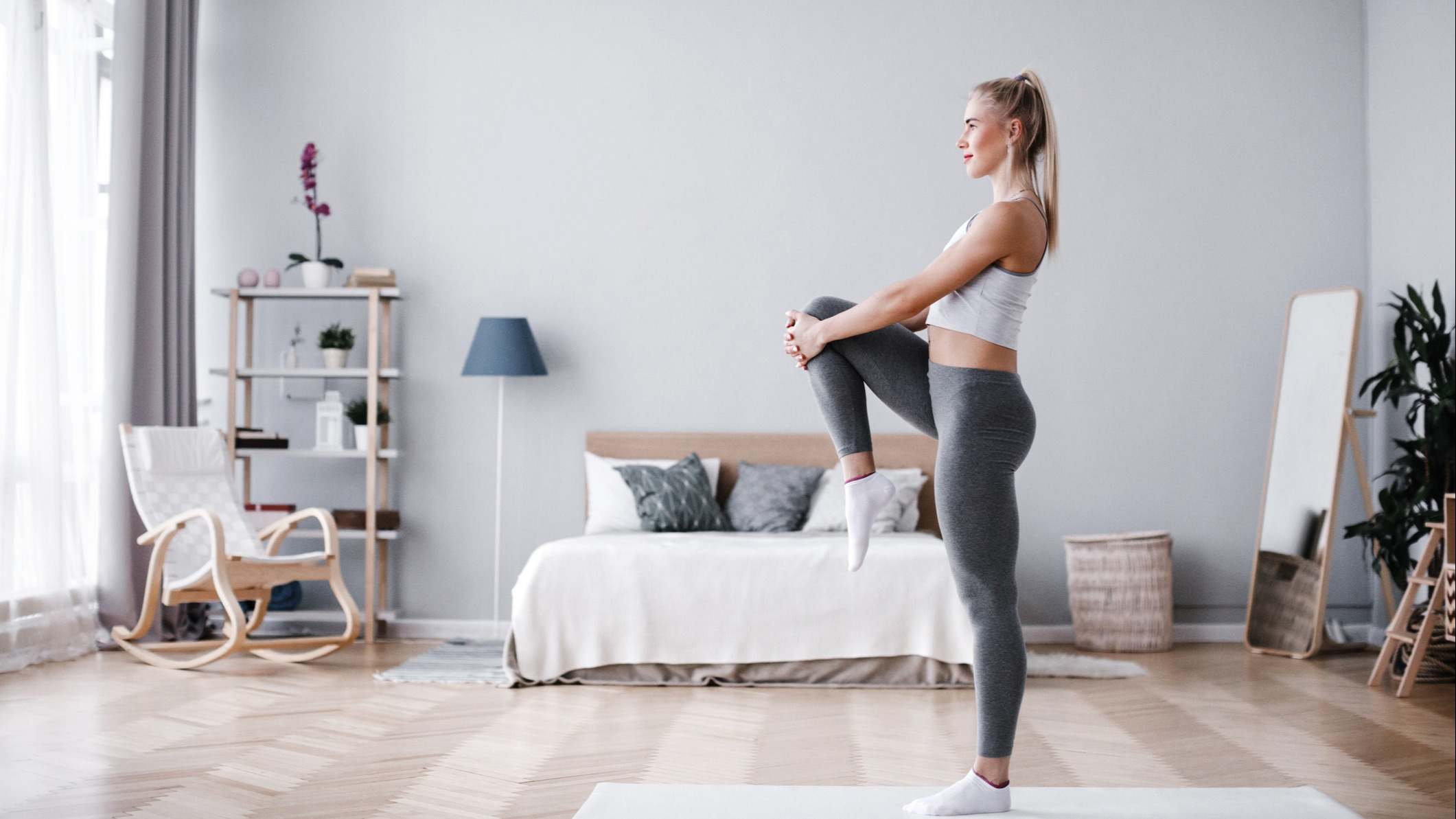 Mujer vestida de deporte haciendo estiramientos en su casa