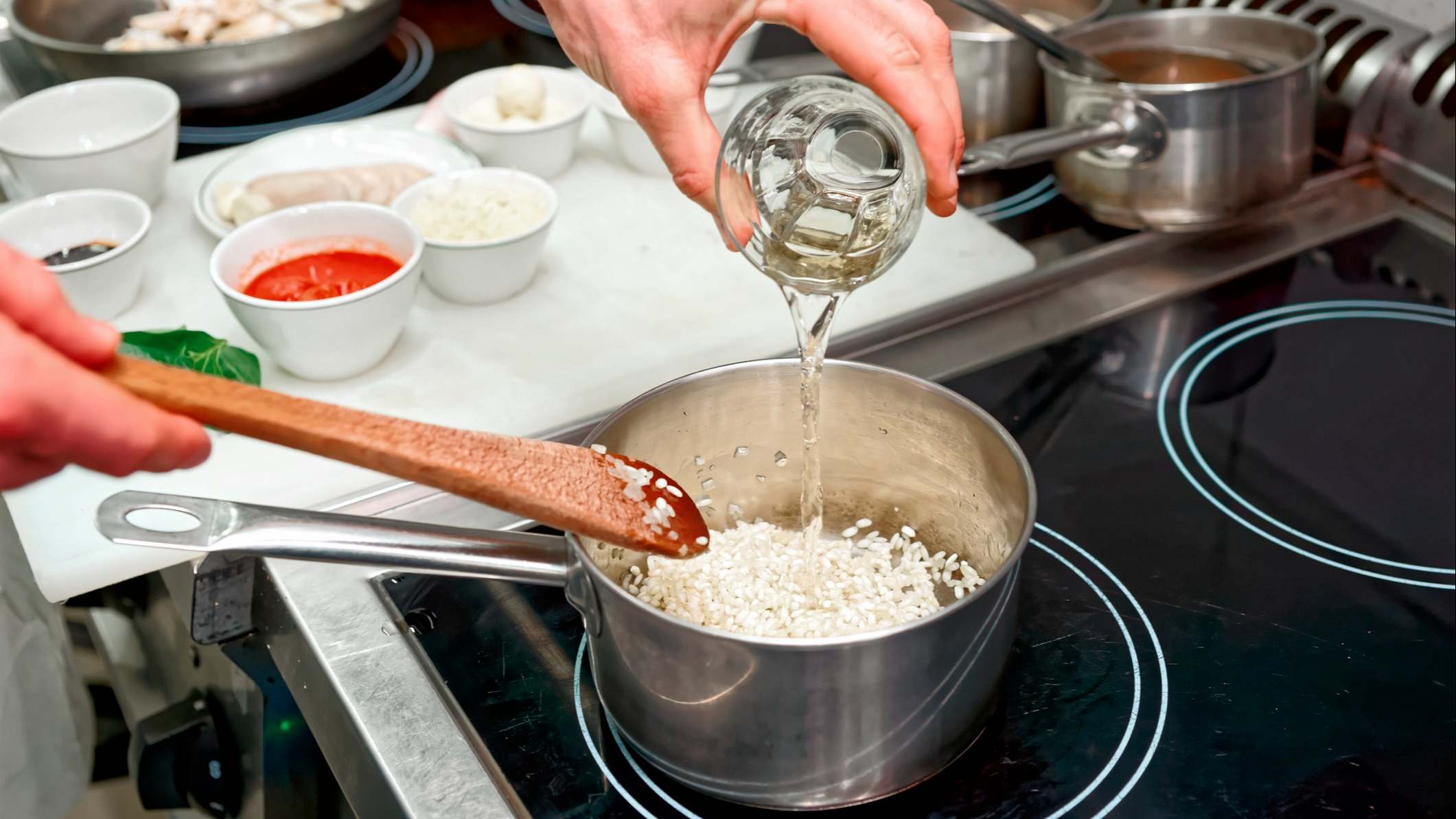 Persona añadiendo un vaso de agua a una olla con arroz