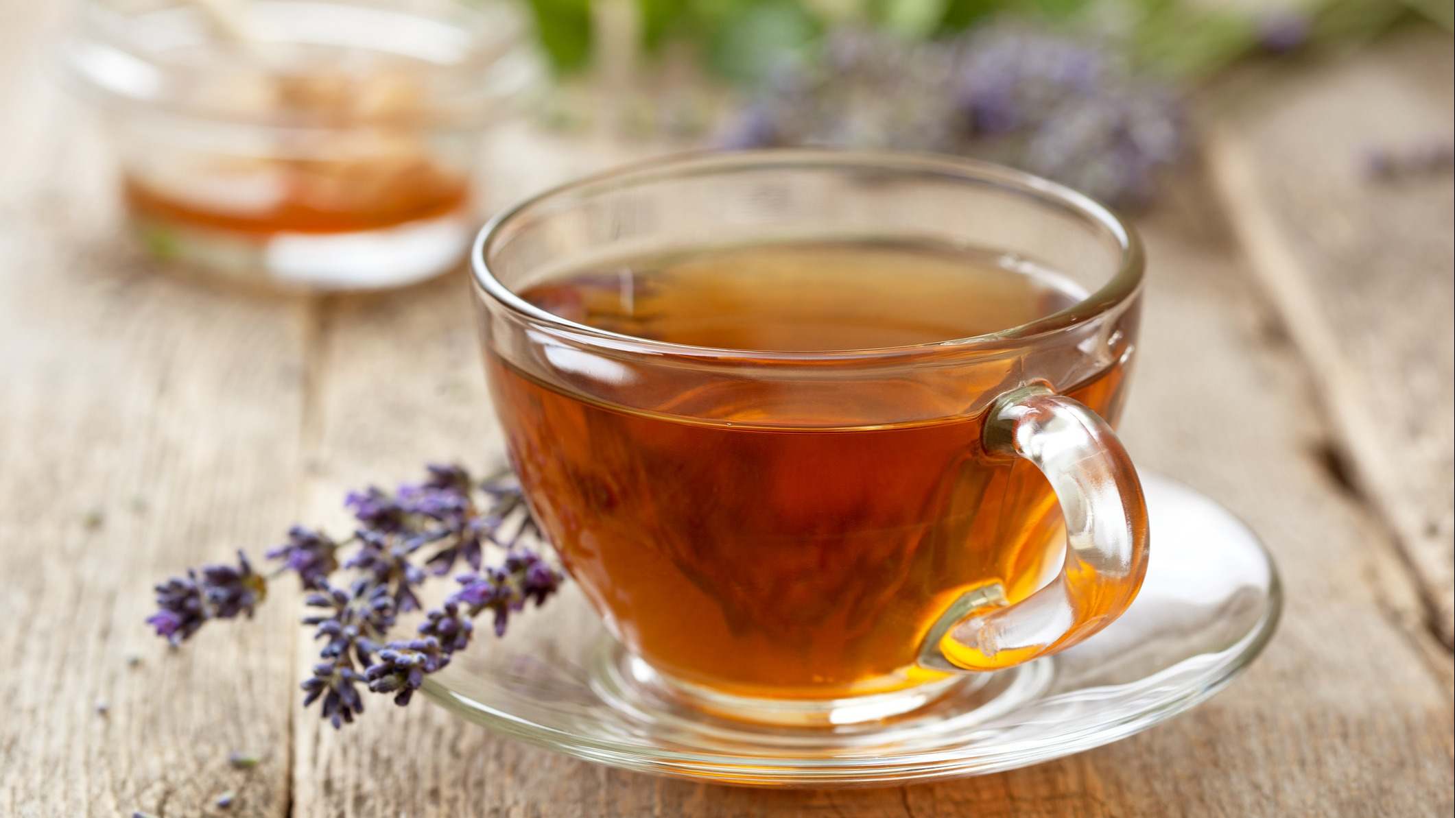 Taza de té de lavanda junto a una rama de la planta