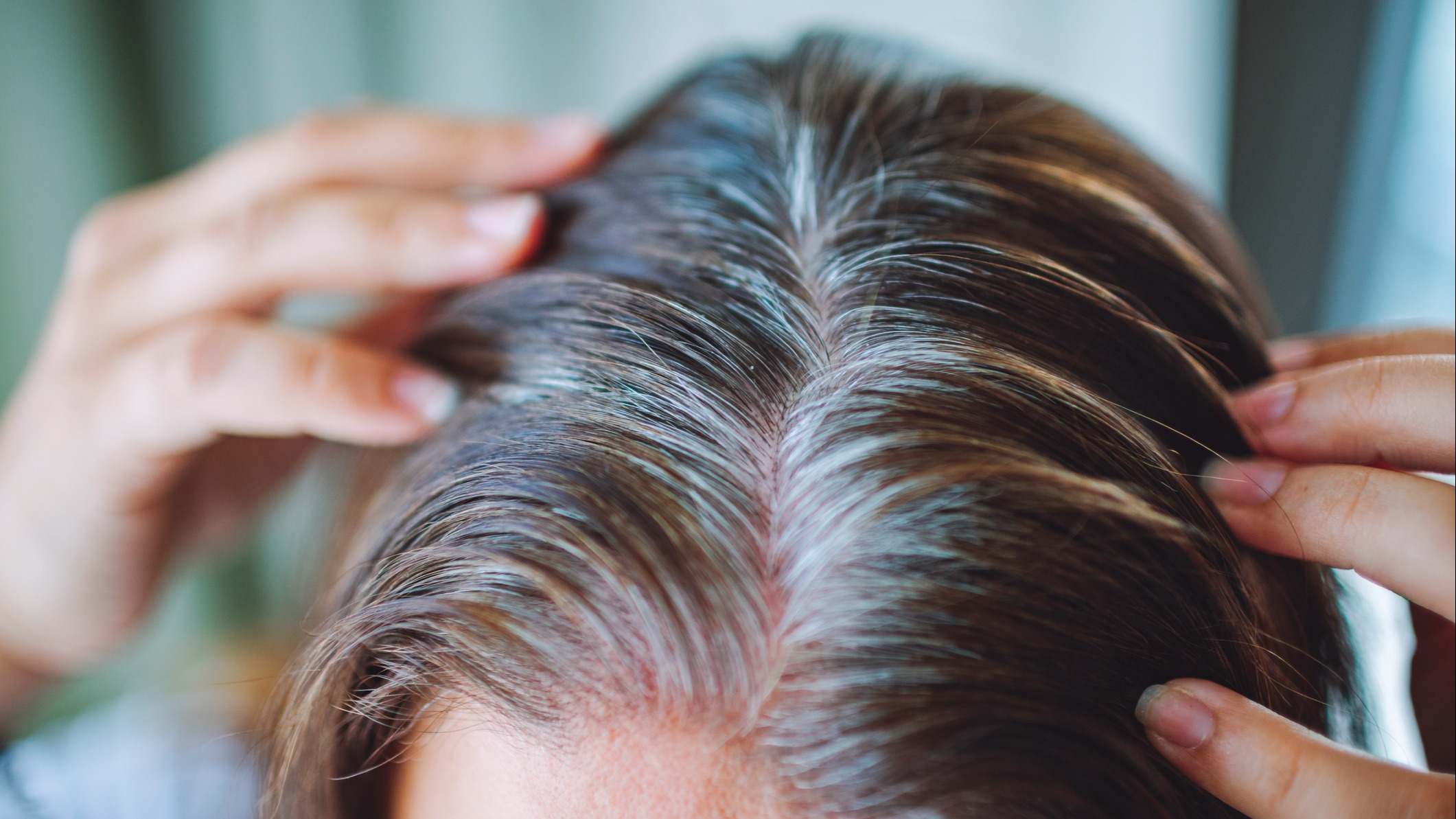 Mujer se toca su pelo con canas