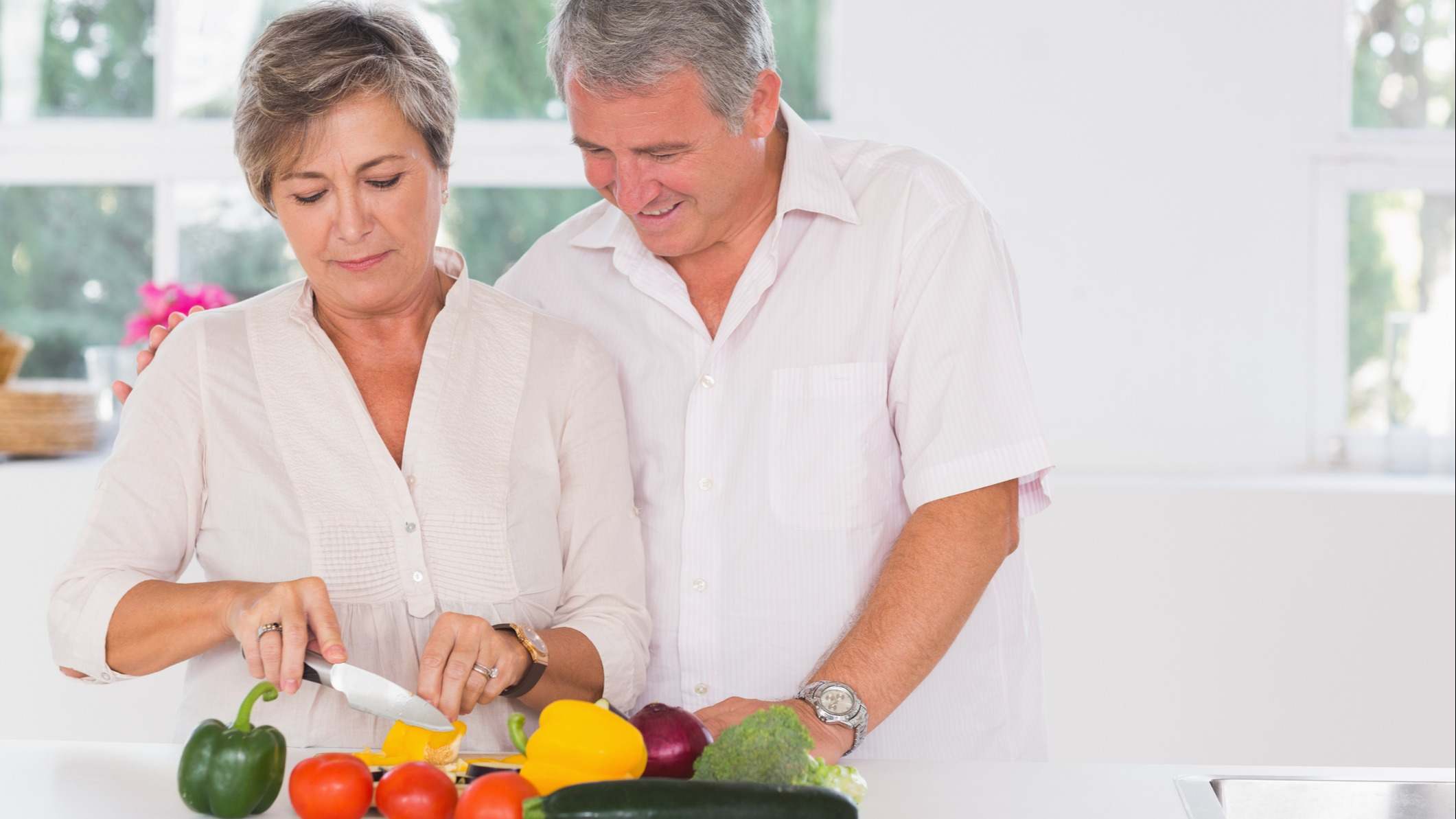 Pareja cortando verduras y hortalizas en una cocina