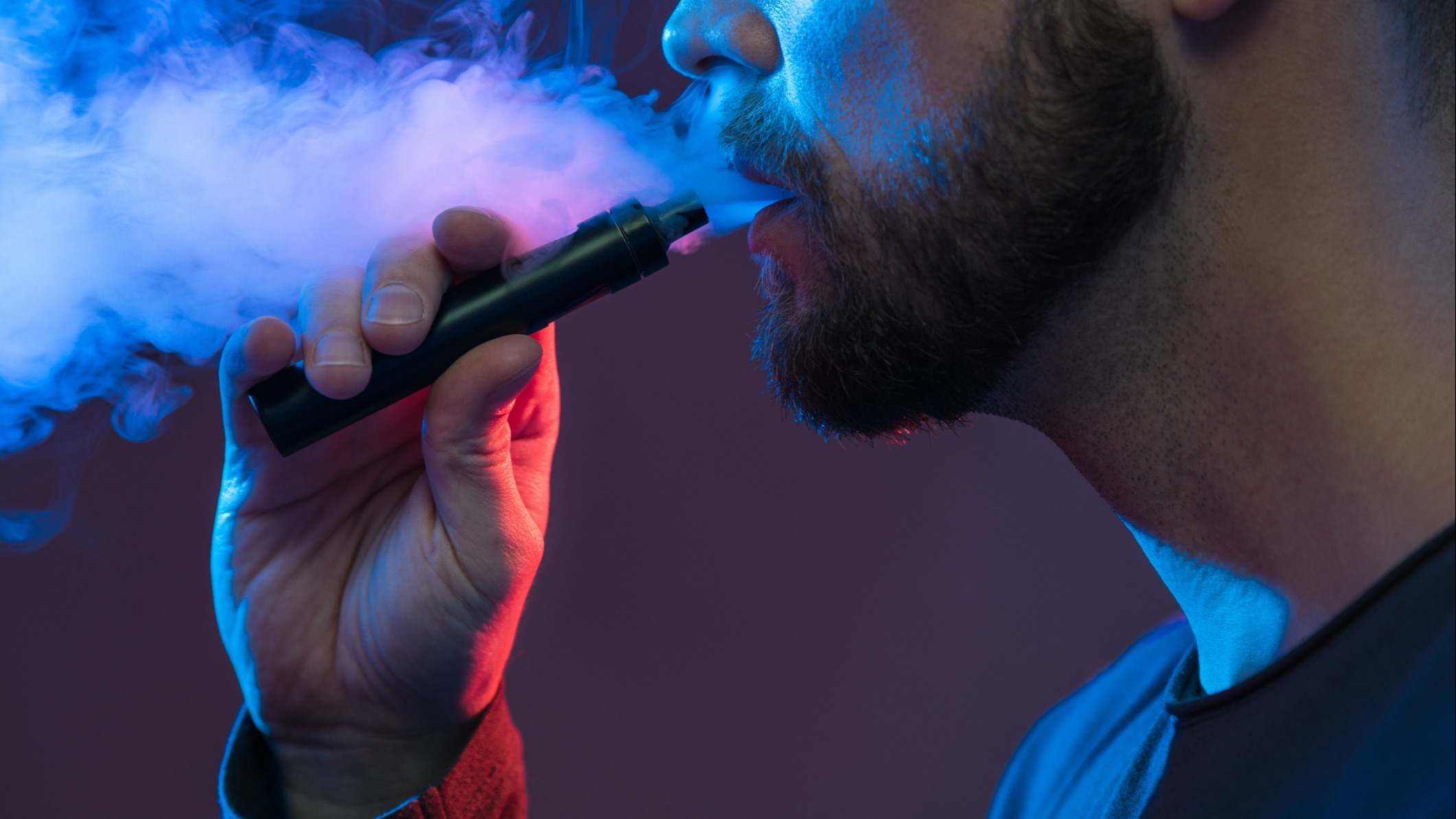 Hombre soltando humo de su boca después de fumar de un cigarrillo electrónico