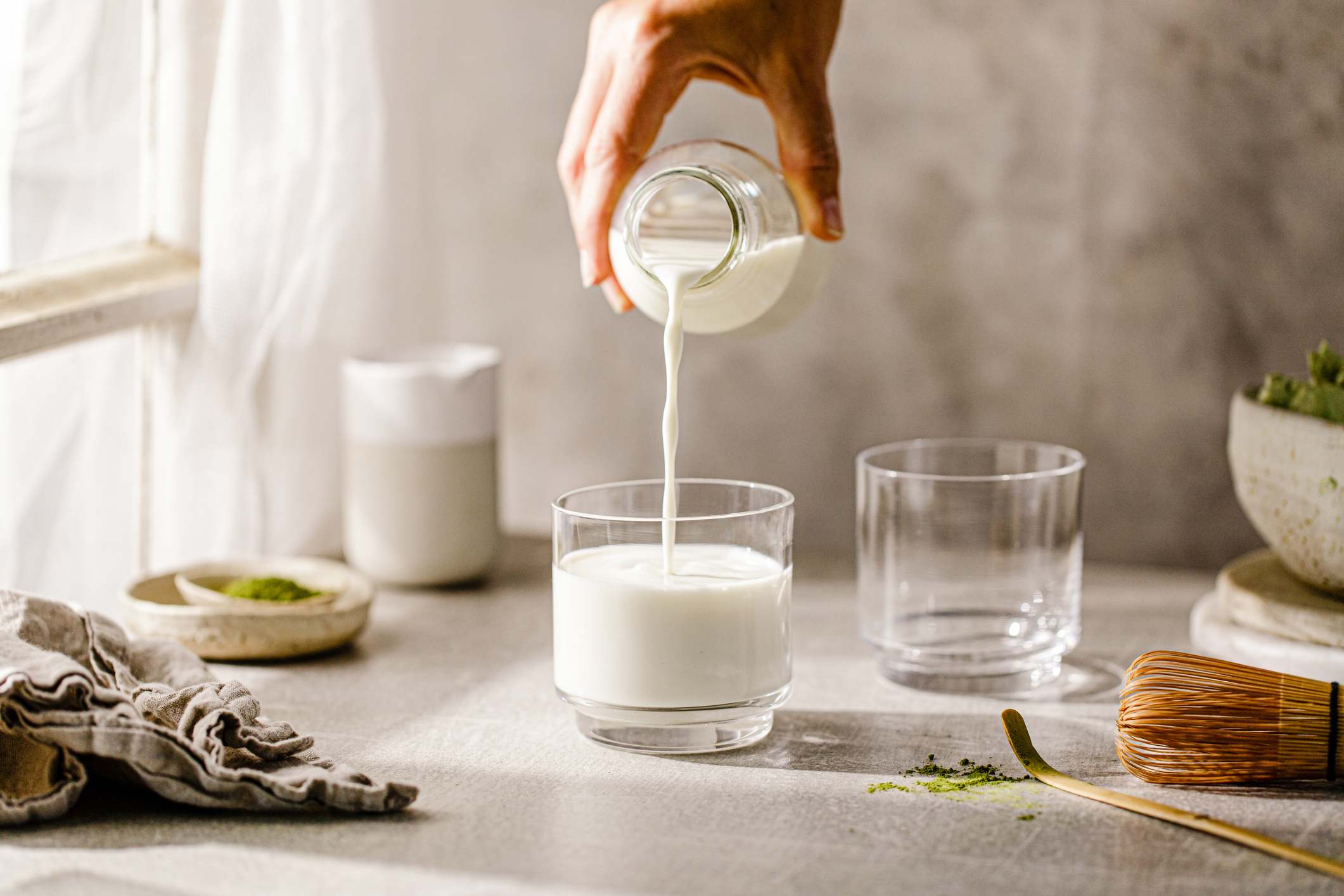 Mano vertiendo leche de una botella en un vaso