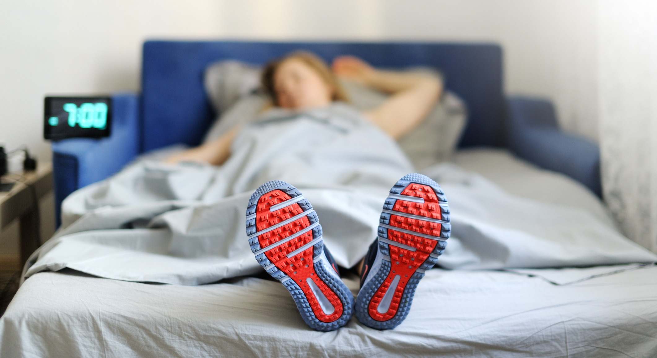 Mujer dormida en la cama con las zapatillas de deporte