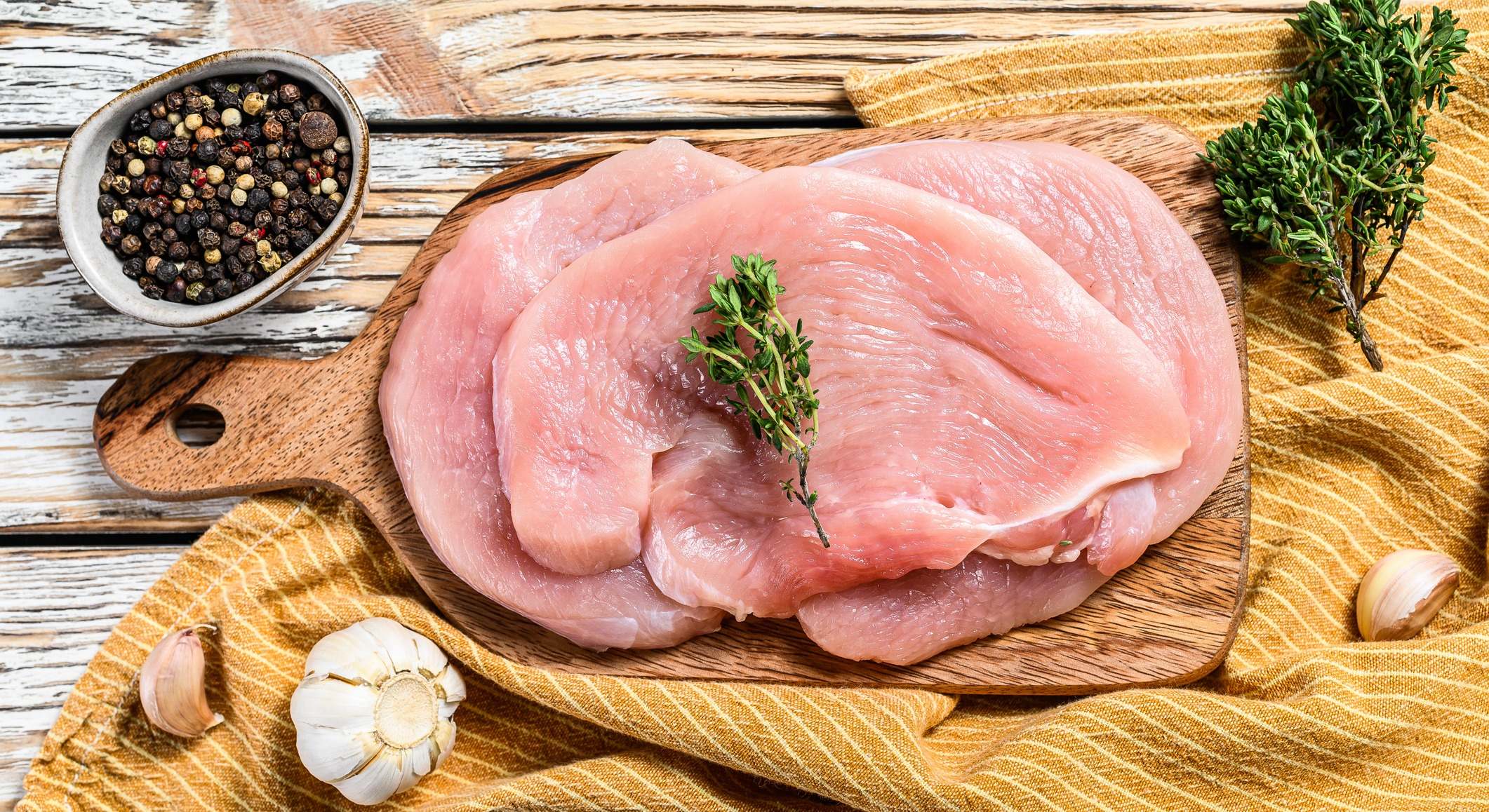 Filetes de pavo fresco con tomillo y pimienta en tabla de cortar