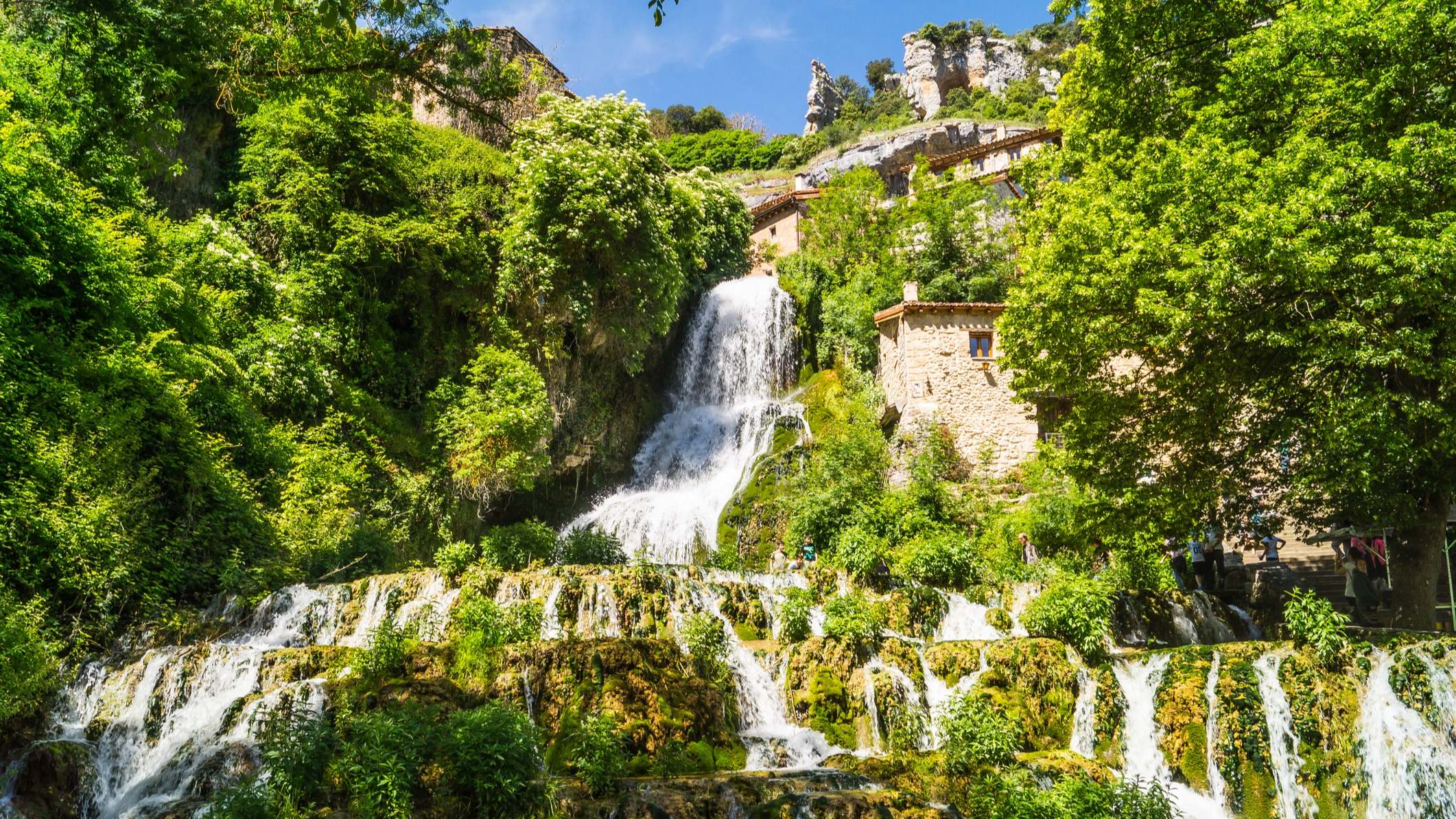Cascada de agua entre árboles en día soleado, Orbaneja del Castillo,
