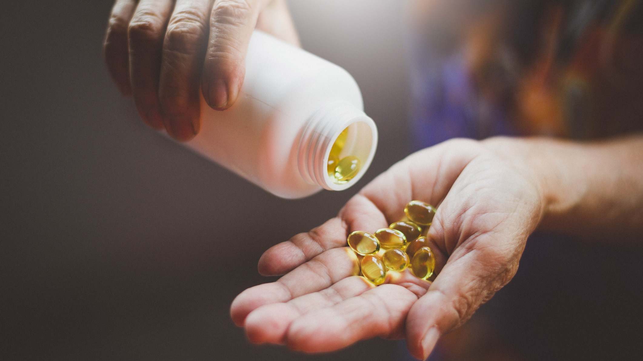 Botella de cápsulas de vitamina D que se vierten en la mano