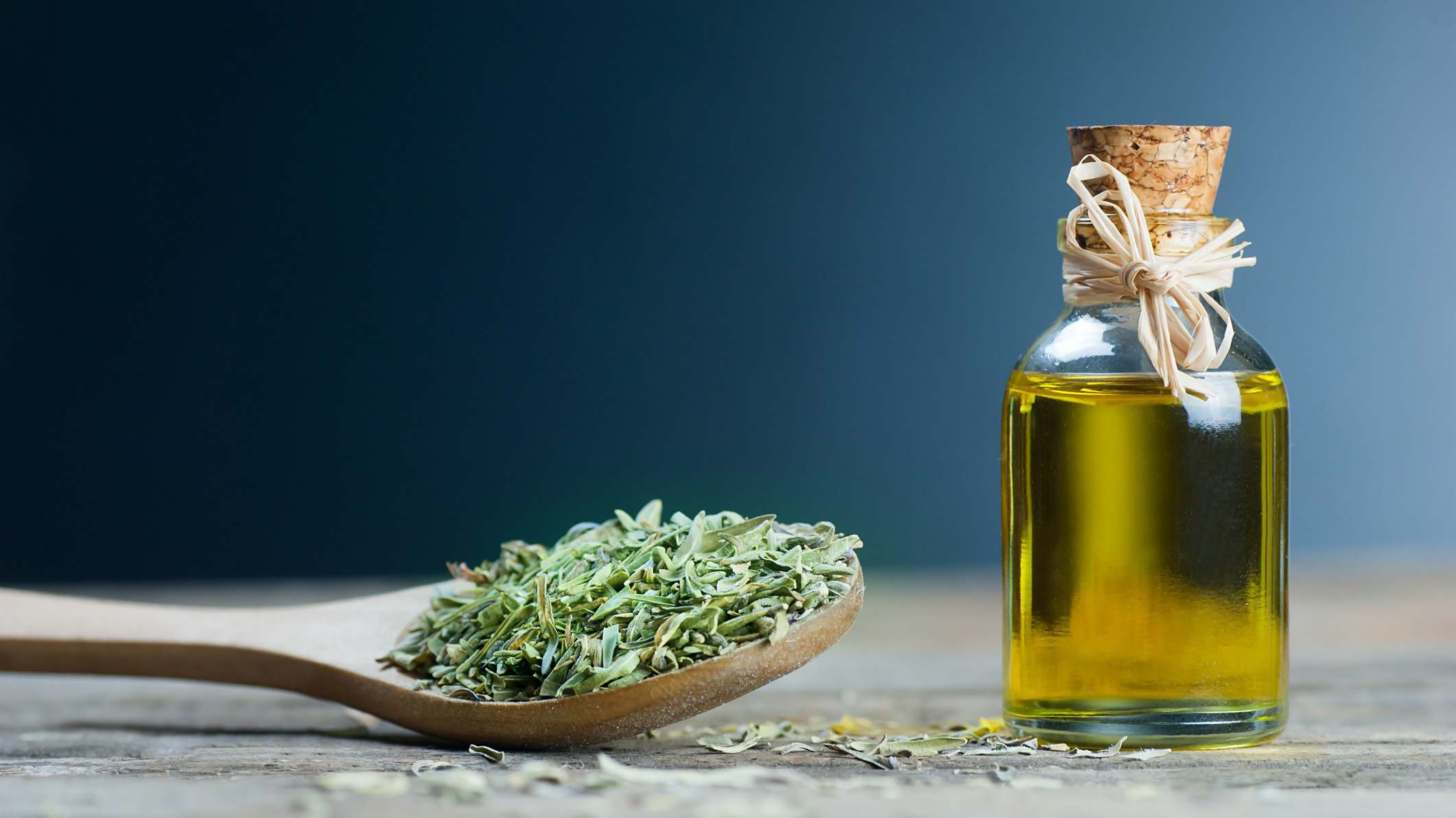 Aceite esencial de tomillo y el montón de tomillo seco en cuchara de madera