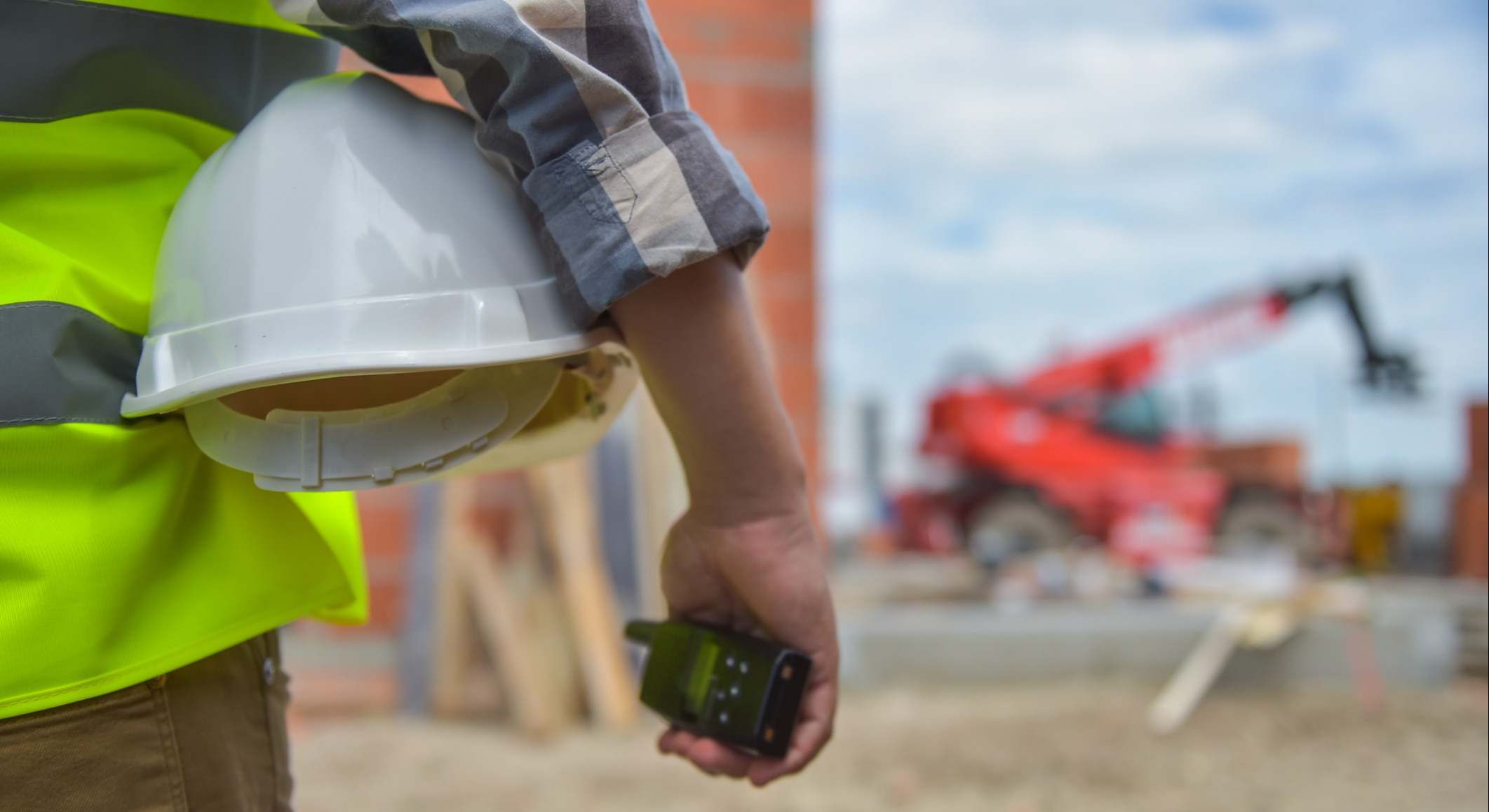 Trabajador sosteniendo un casco con fondo de obra
