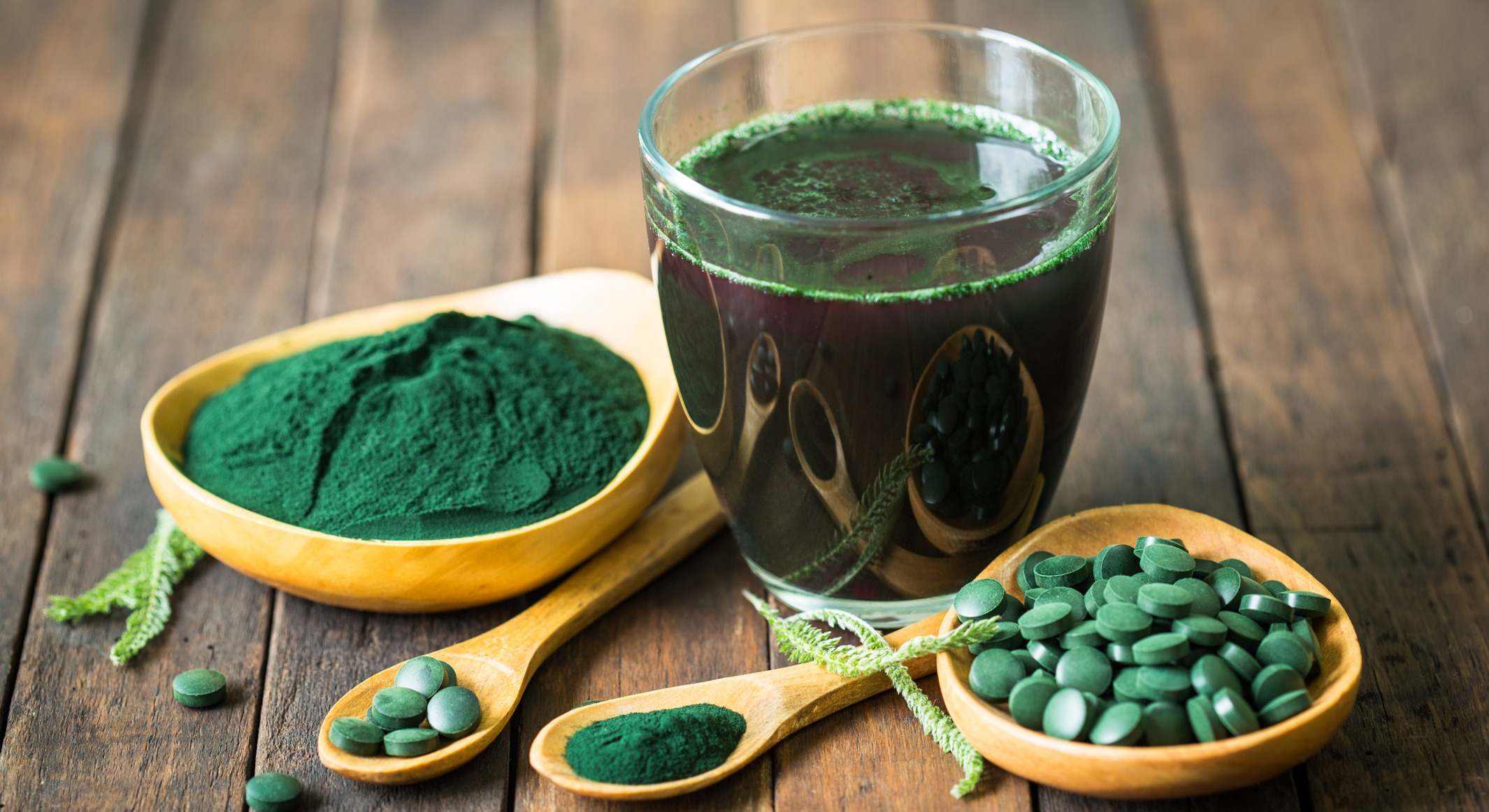 Espirulina en forma desecada, tabletas o en polvo sobre una mesa de madera