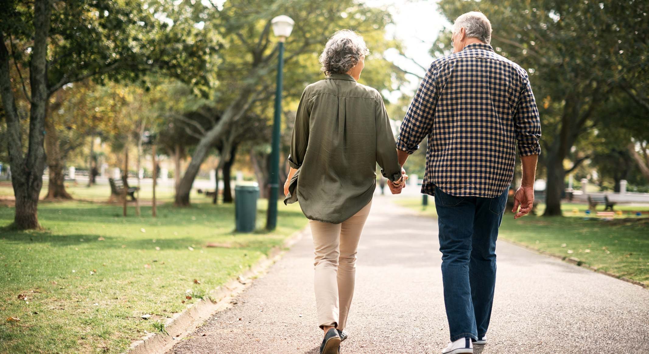 Pareja paseando de la mano por un parque