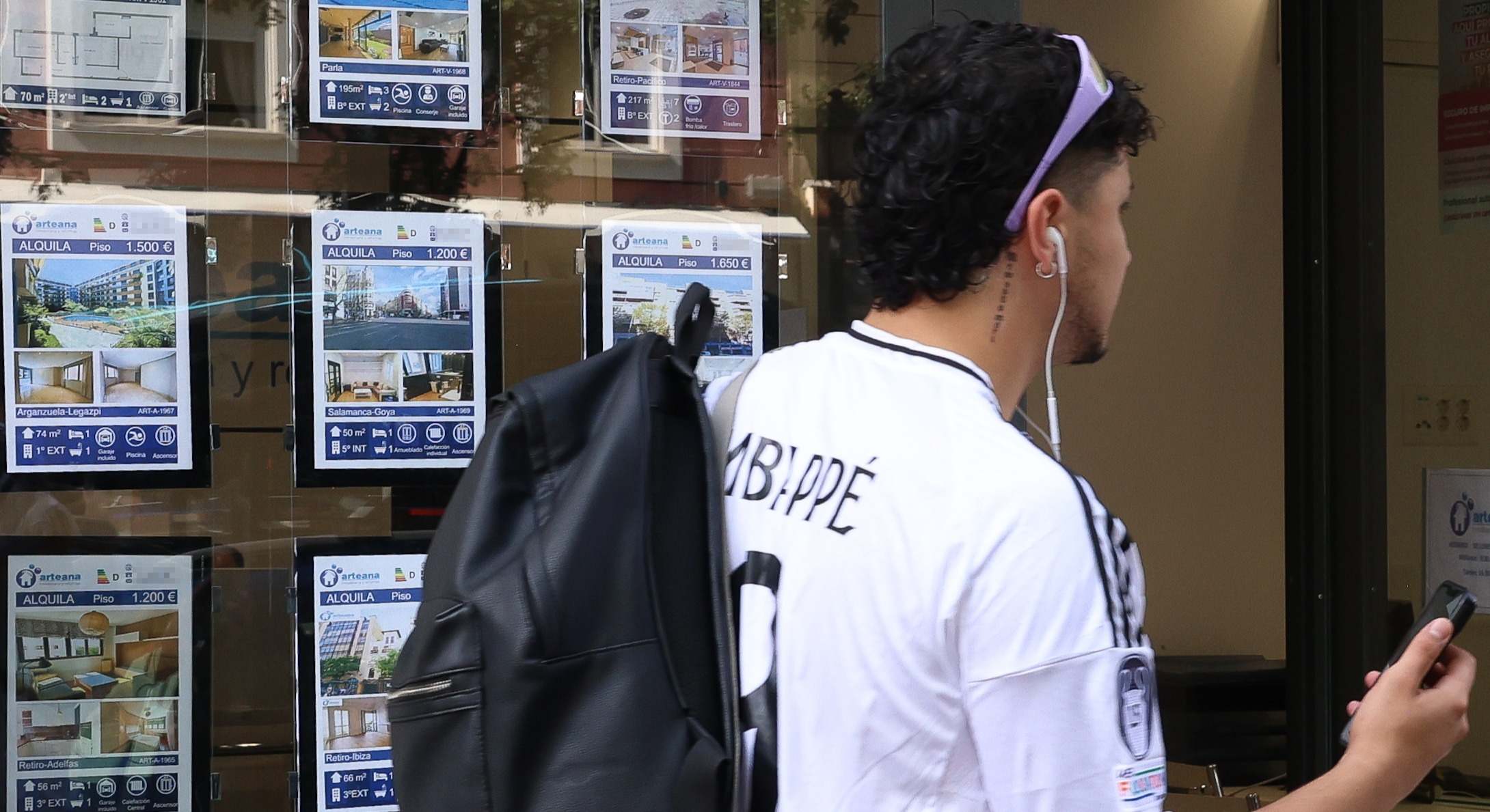 Un joven pasa junto a un escaparate de una inmobiliaria.