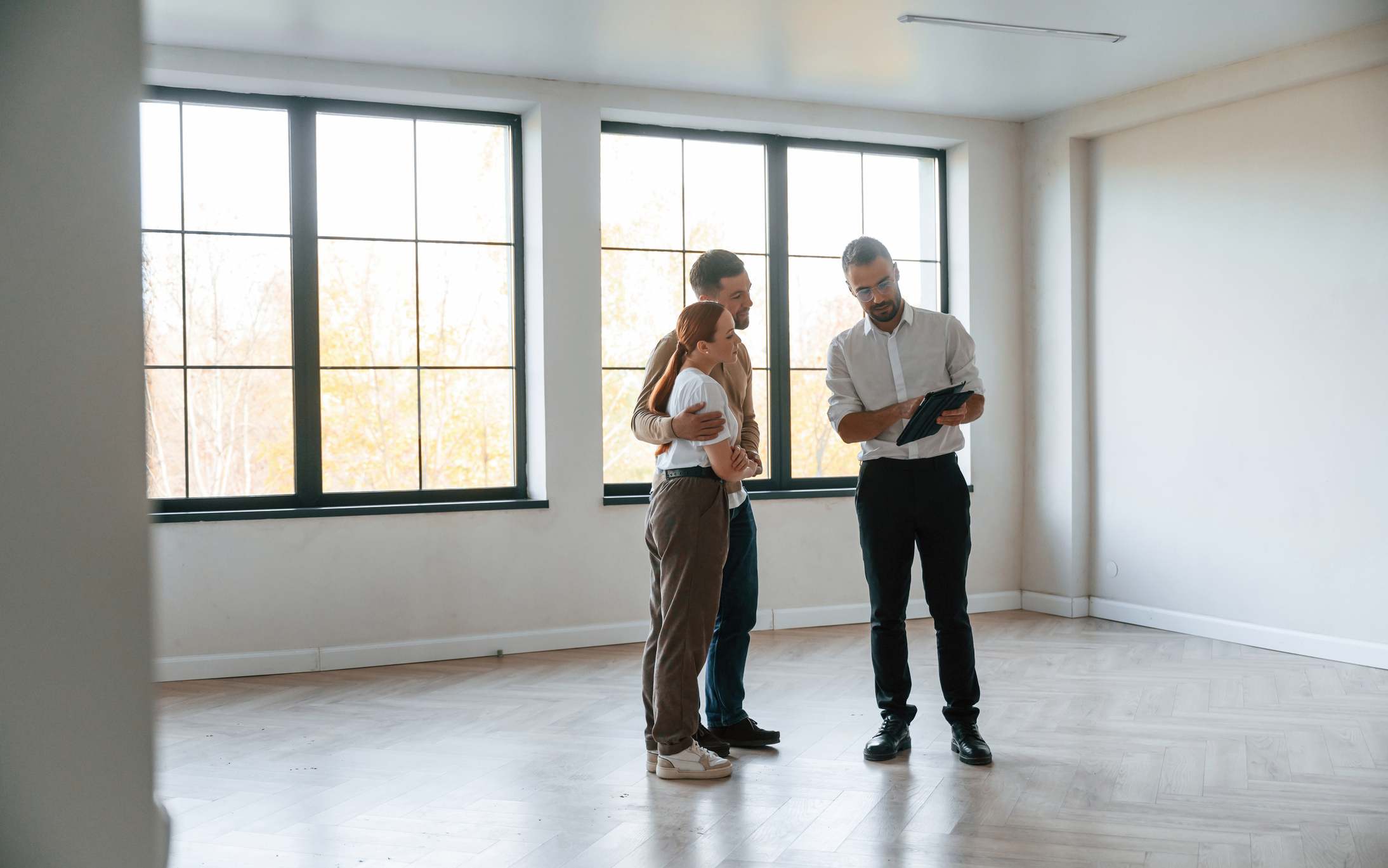 Habitación vacía. Agente inmobiliario muestra un apartamento a una pareja joven