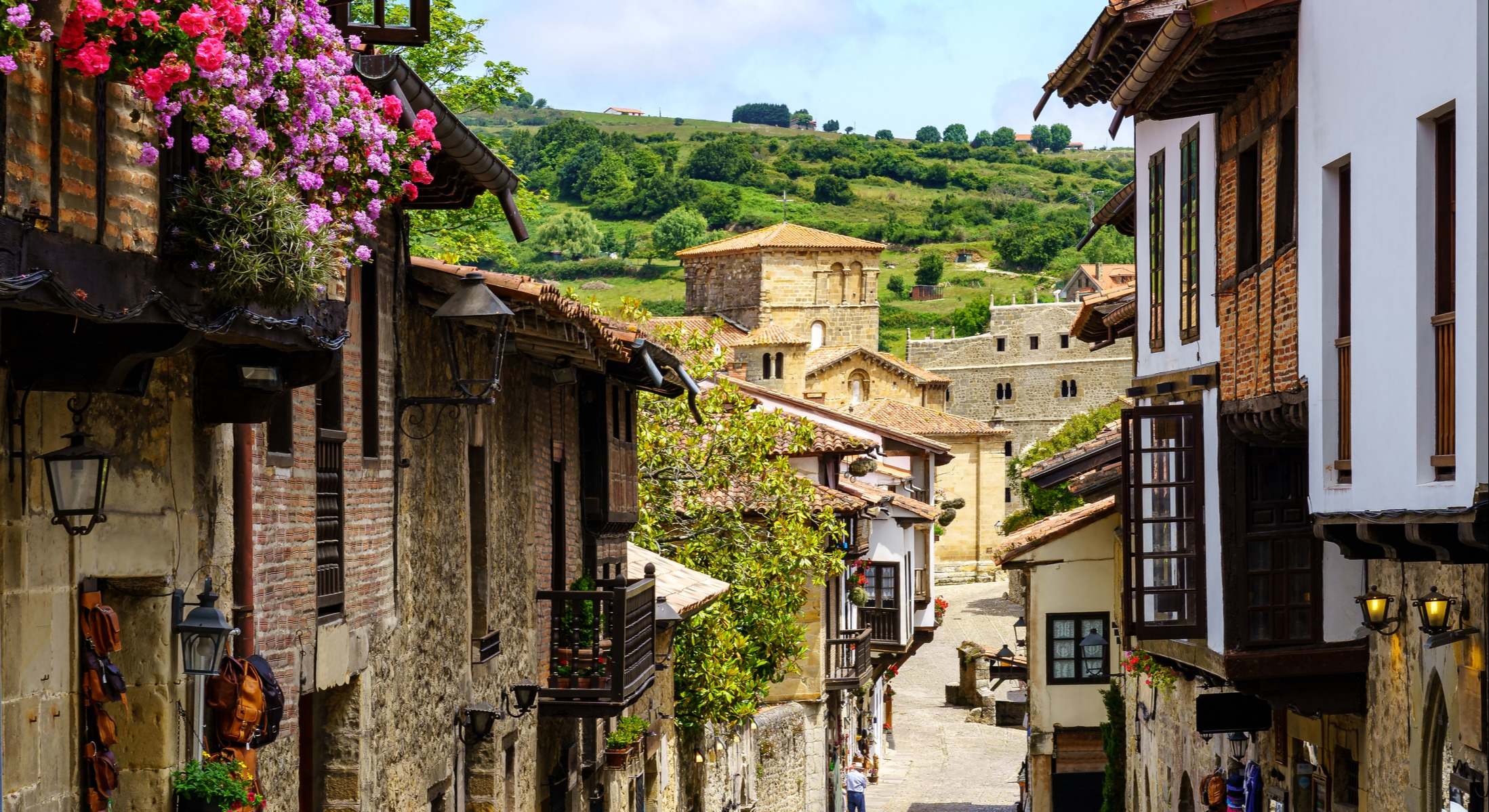 Vista en perspectiva de las casas alineadas en la estrecha calle del casco antiguo y la iglesia en el fondo en Santillana del Mar