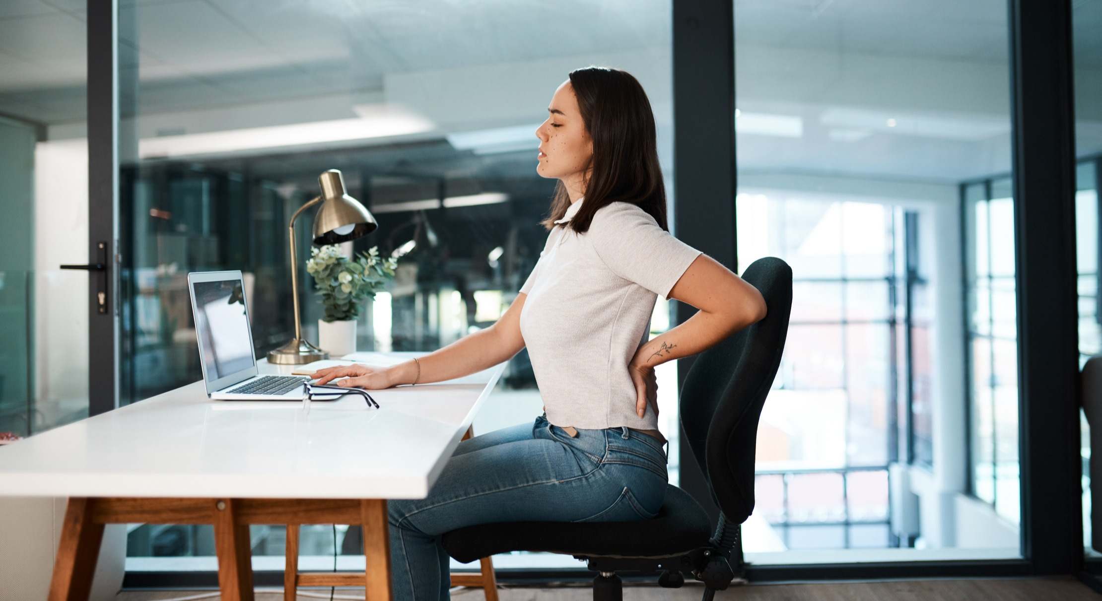 Mujer sentada en el trabajo con dolor de espalda