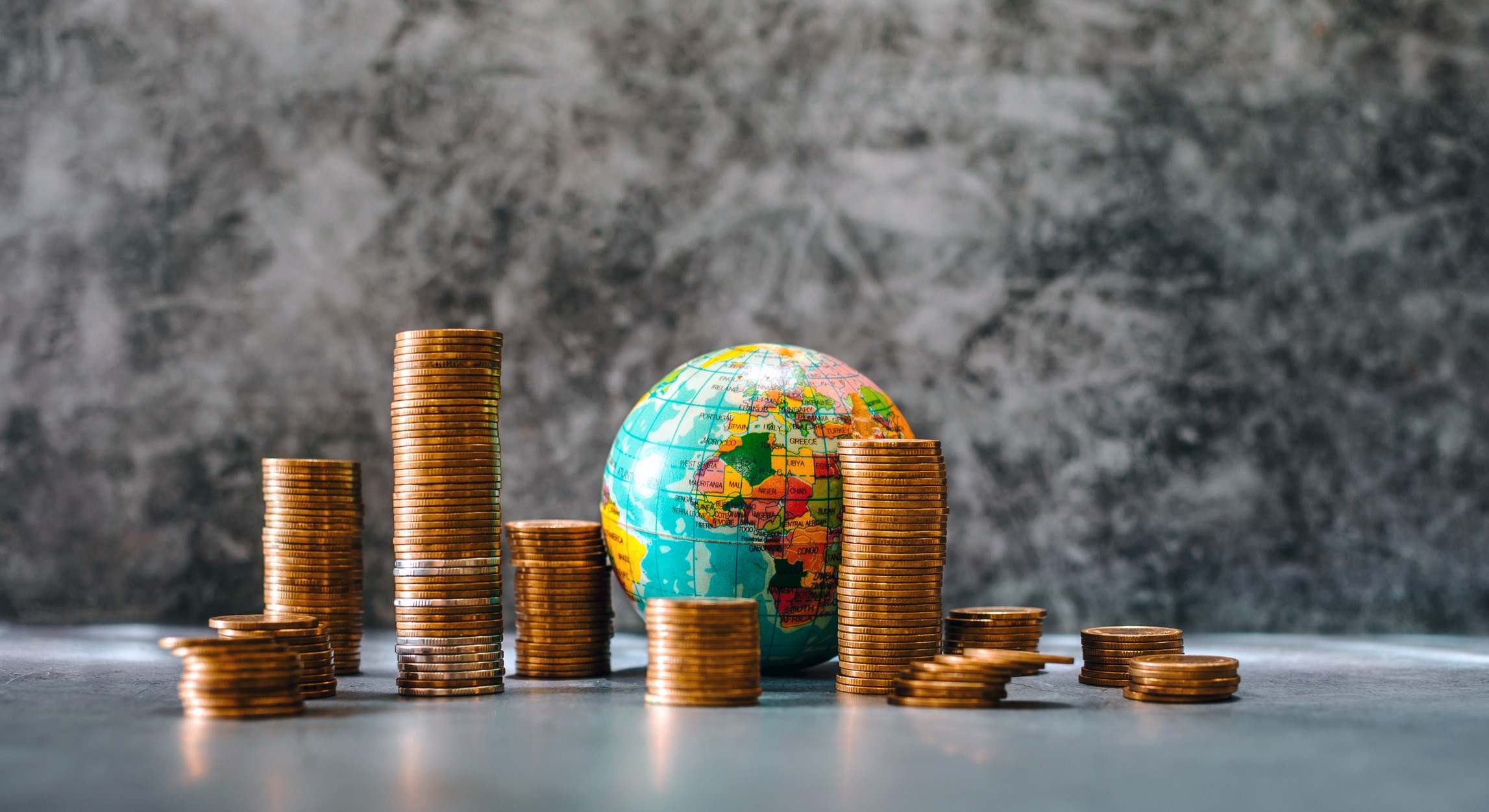 Dinero alrededor de una bola del mundo. Imagen: iStock. 