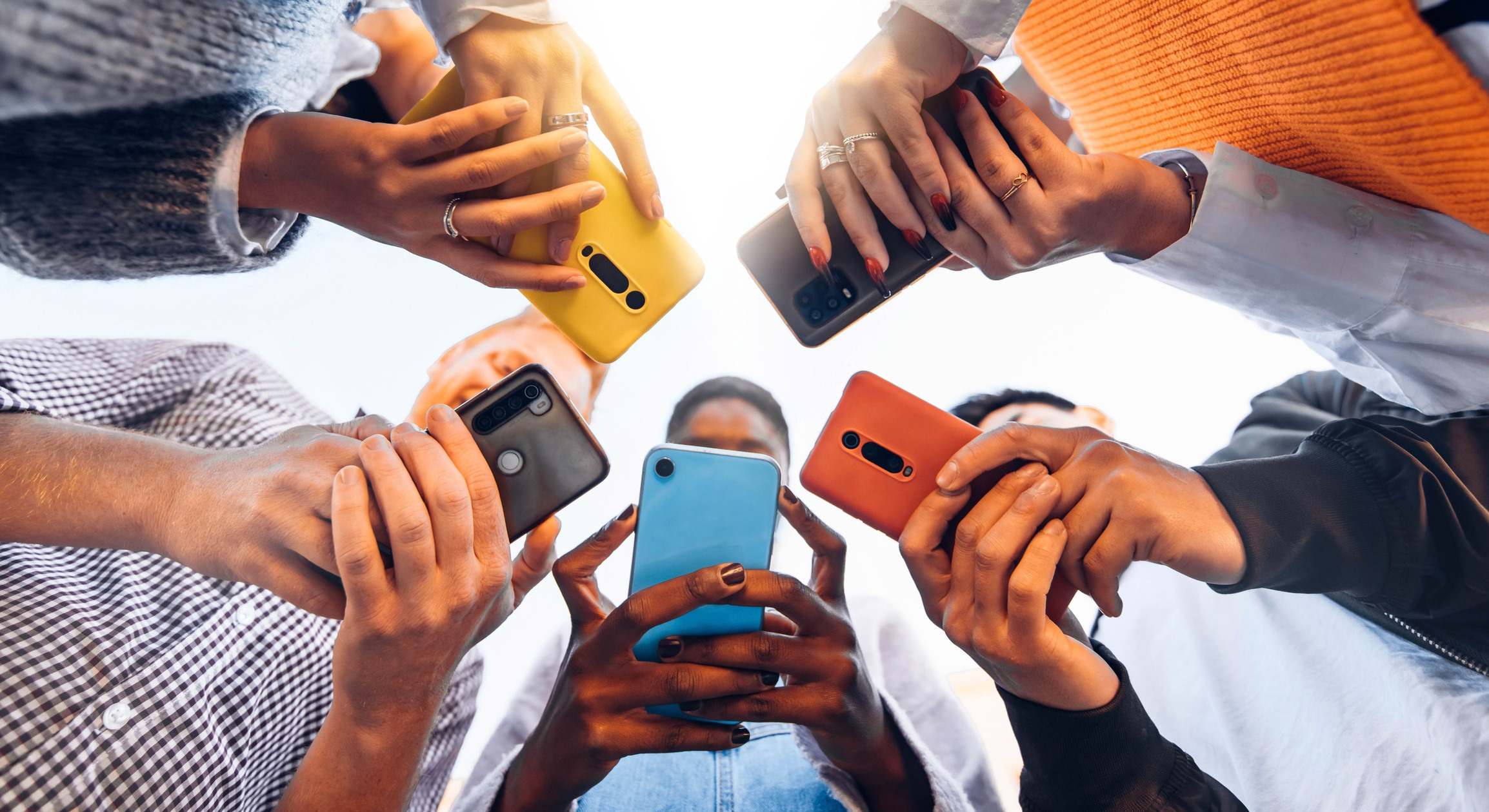 Adolescentes en círculo sosteniendo teléfonos móviles