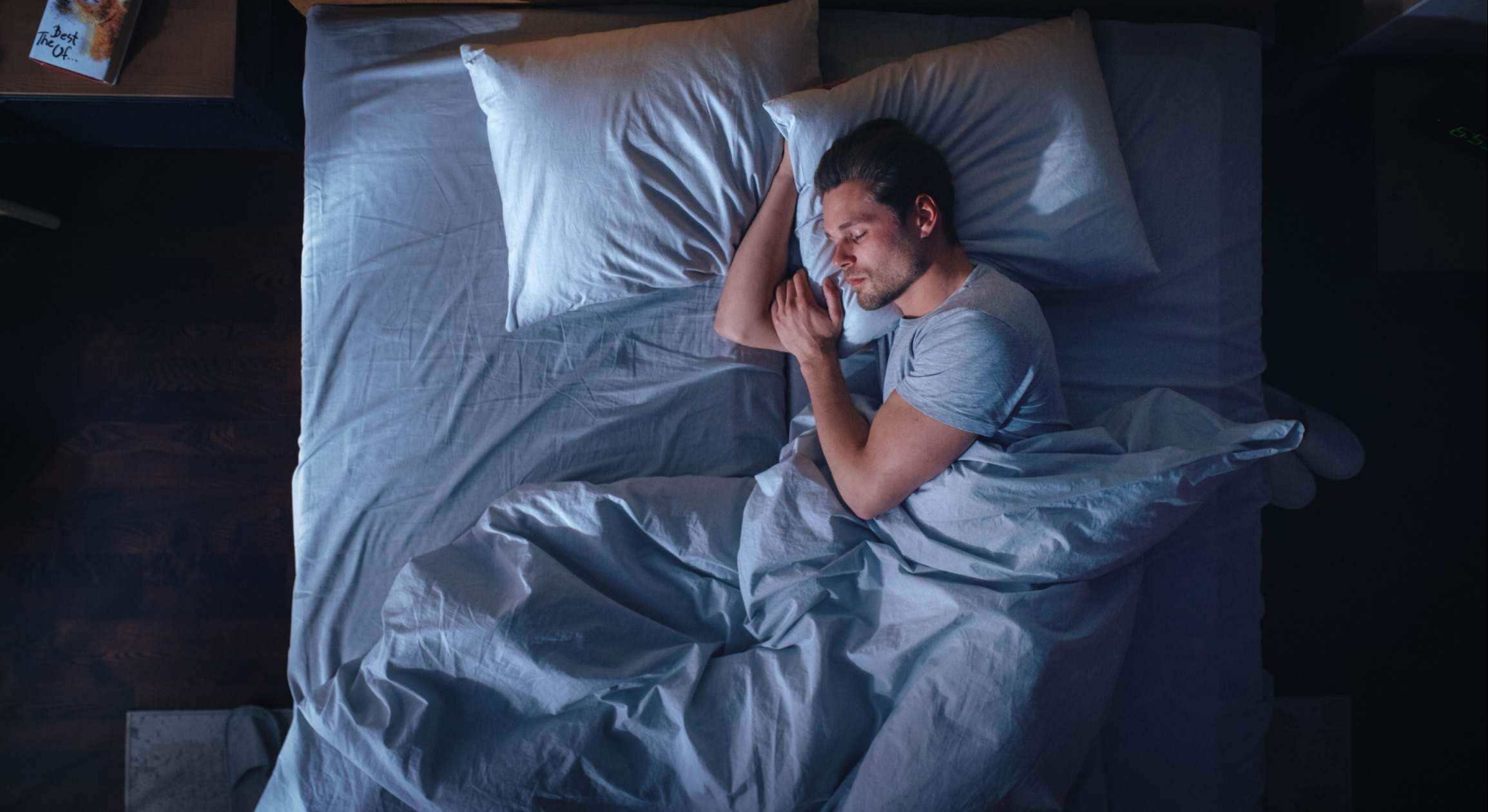 Joven durmiendo cómodamente en una cama por la noche