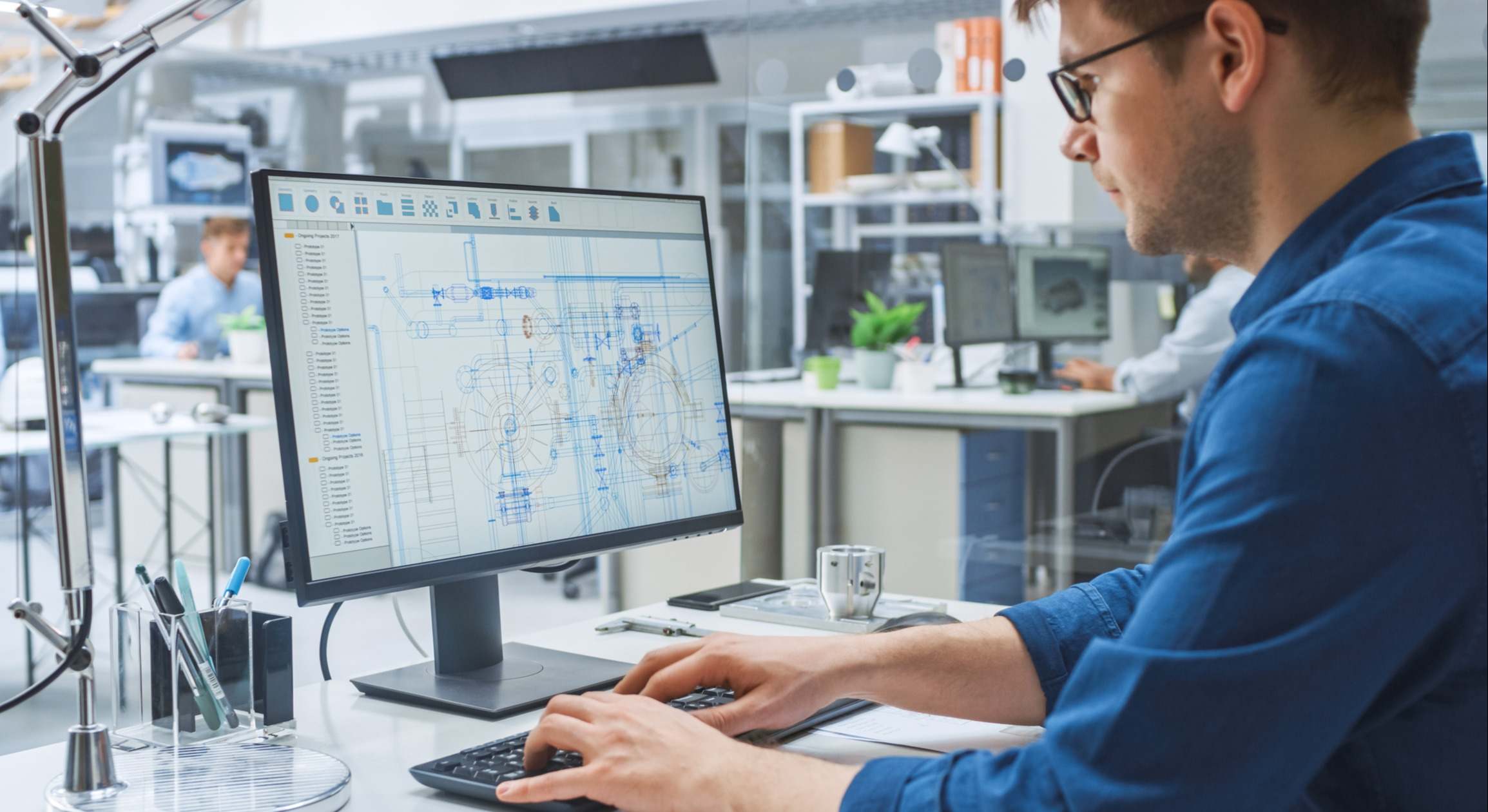 Sobre la toma de hombro de ingeniero que trabaja con software CAD en computadora de escritorio, la pantalla muestra borradores técnicos y dibujos. En la instalación de ingeniería de fondo especializada en diseño industrial - Foto de stock
