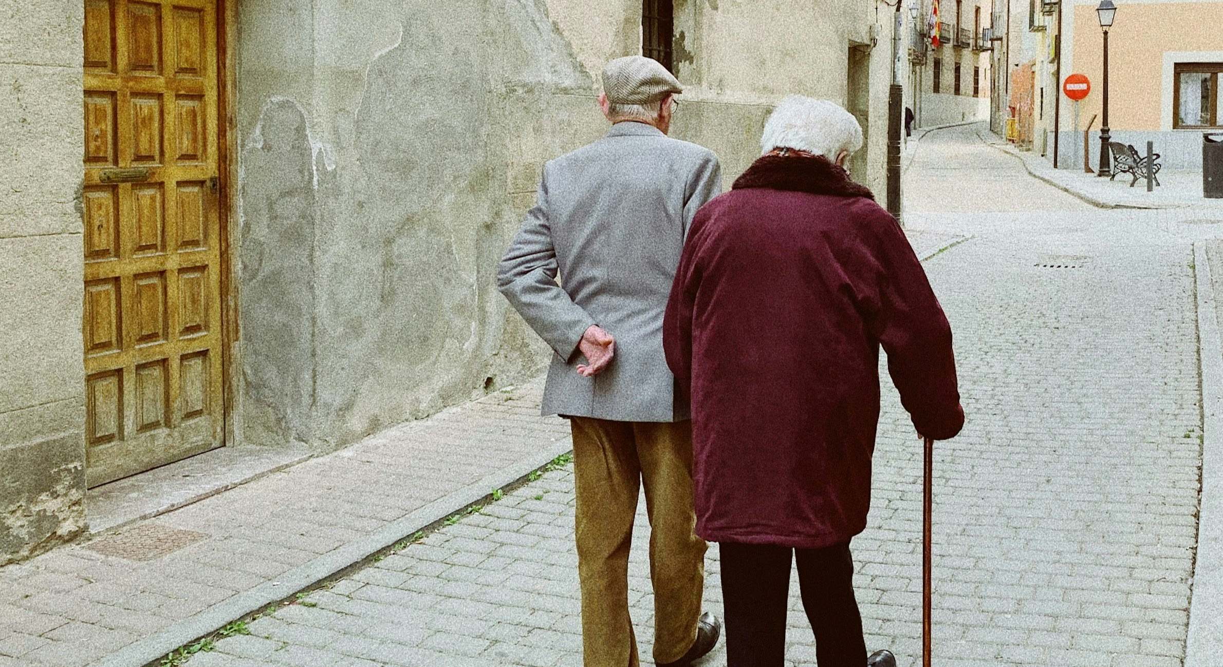Dos personas de avanzada edad pasean juntos por una calle ancha