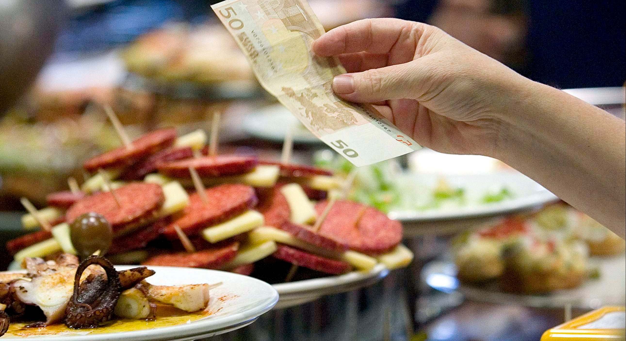 Imagen de archivo de comida en un bar y una persona ofreciendo un billete. Foto: Javier Etxezarreta.