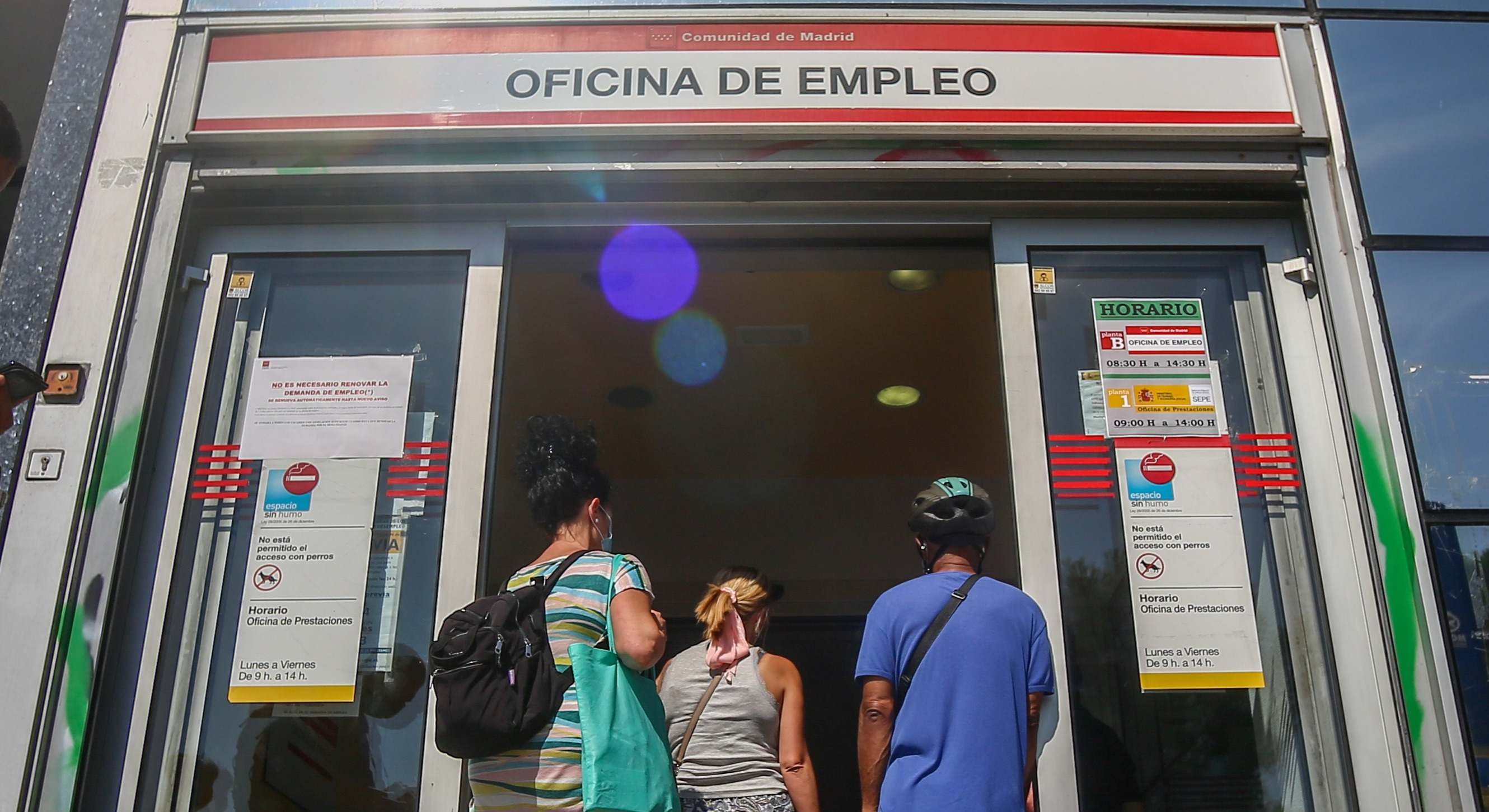 Varias personas hacen cola para entrar a una oficina de empleo.